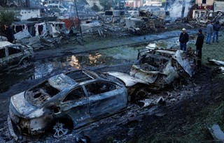 People look at cars damaged during Russian missile and drone strikes at a garage in Kyiv