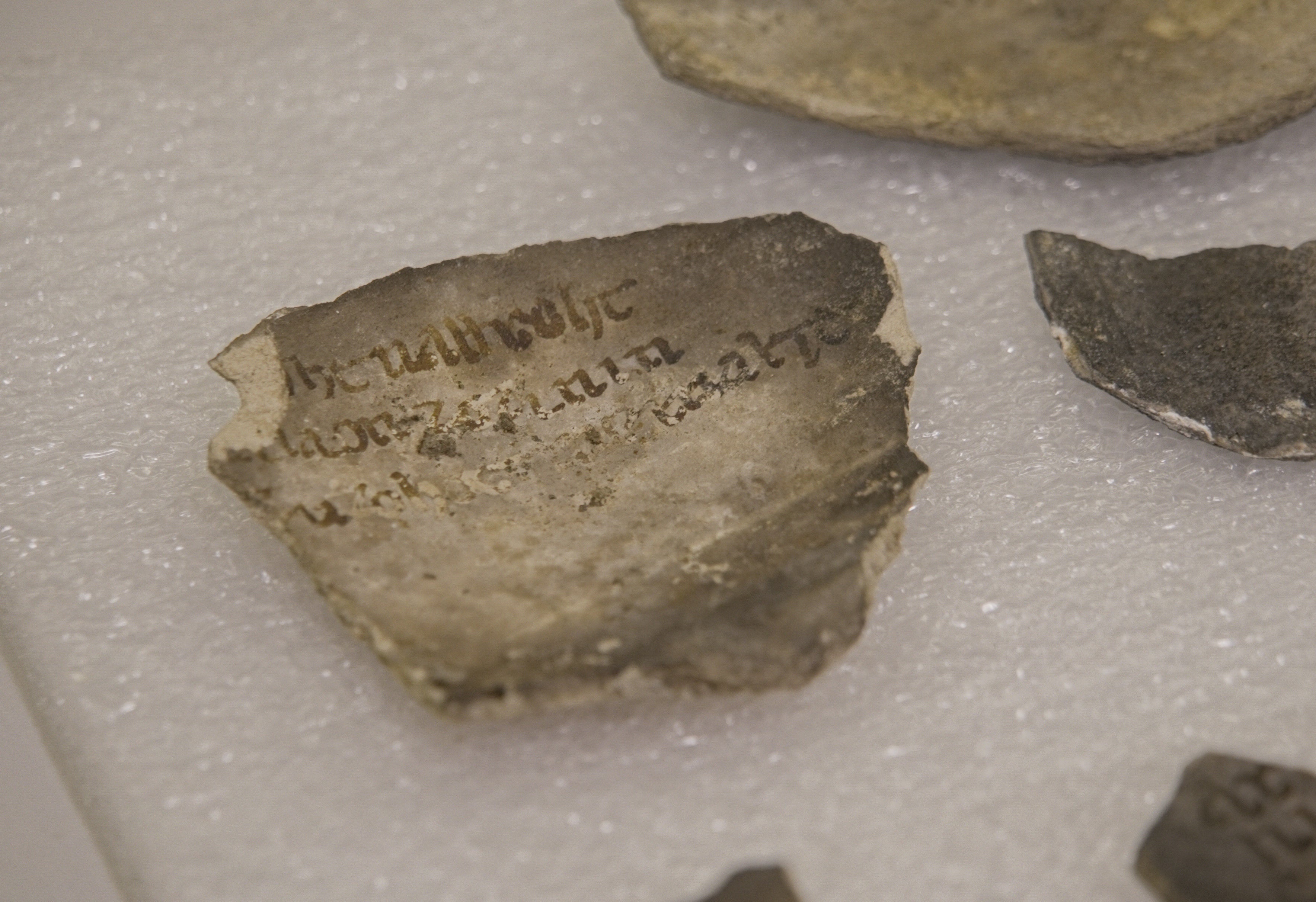 A fragment bearing an inscription is photographed among artifacts discovered during excavations outside Notre-Dame Cathedral