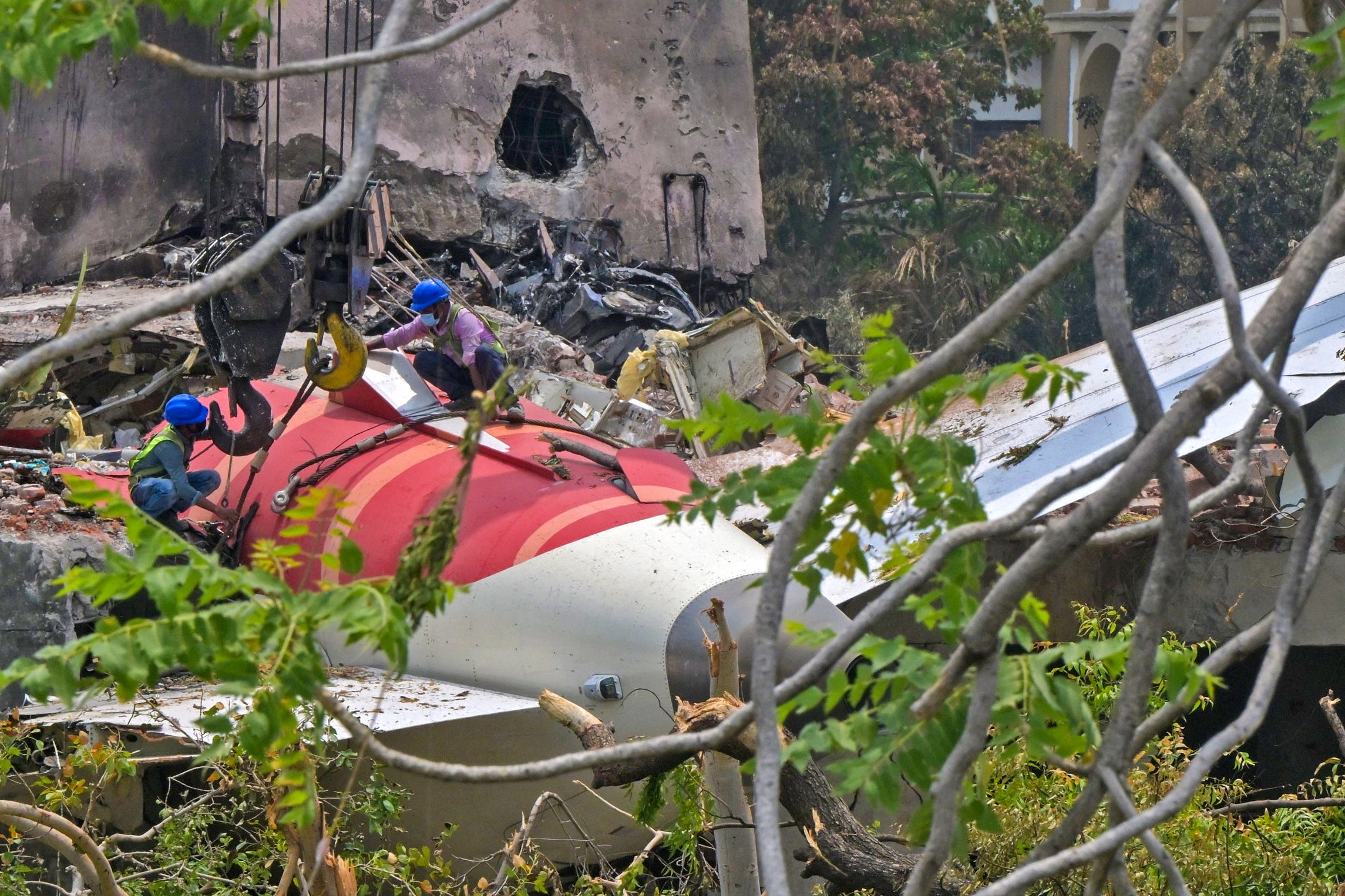 Workers removing aeroplane's tail from the wreckage after the 12 June Air India flight 171 crash, is pictured in a residential area near the airport in Ahmedabad on 14 June 2025