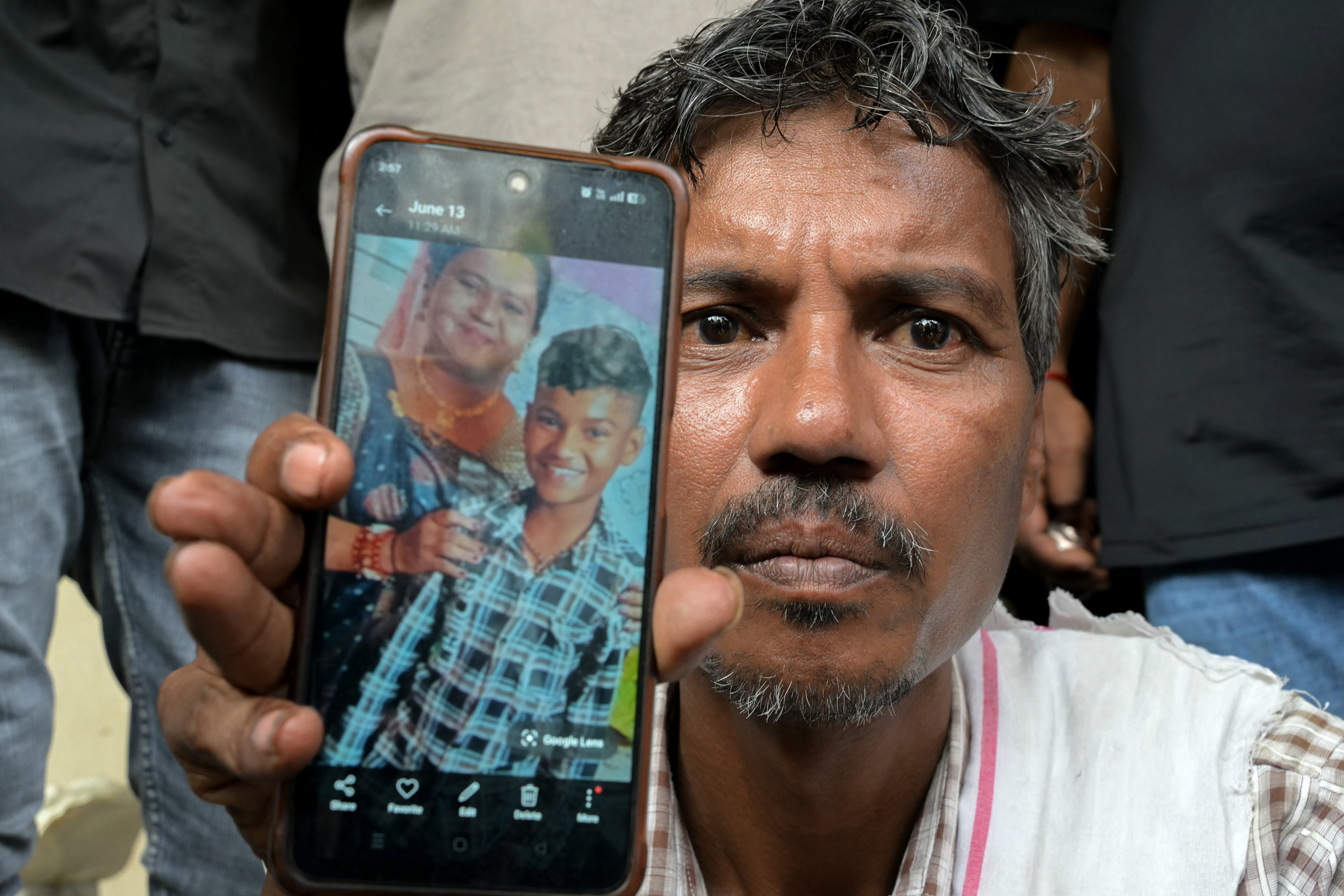 Suresh Patni shows a picture of his wife and son as he waits outside a hospital in Ahmedabad on 15 June 2025
