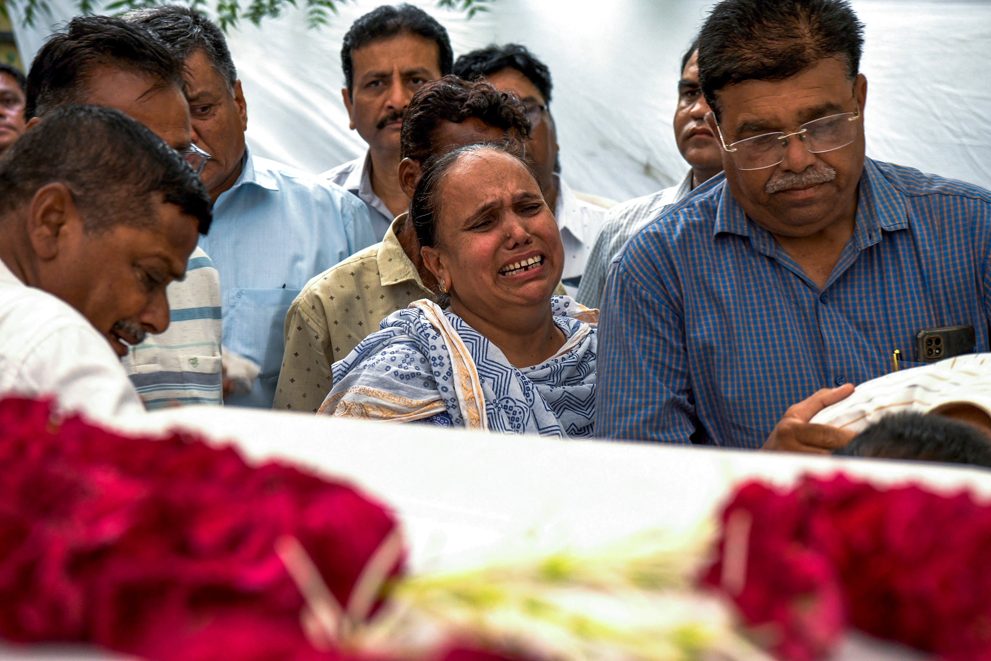 Relatives grieve near the coffin containing the remains of Rozar David Christian, a victim of the Air India plane crash, outside his home in Ahmedabad, India, on 15 June 2025