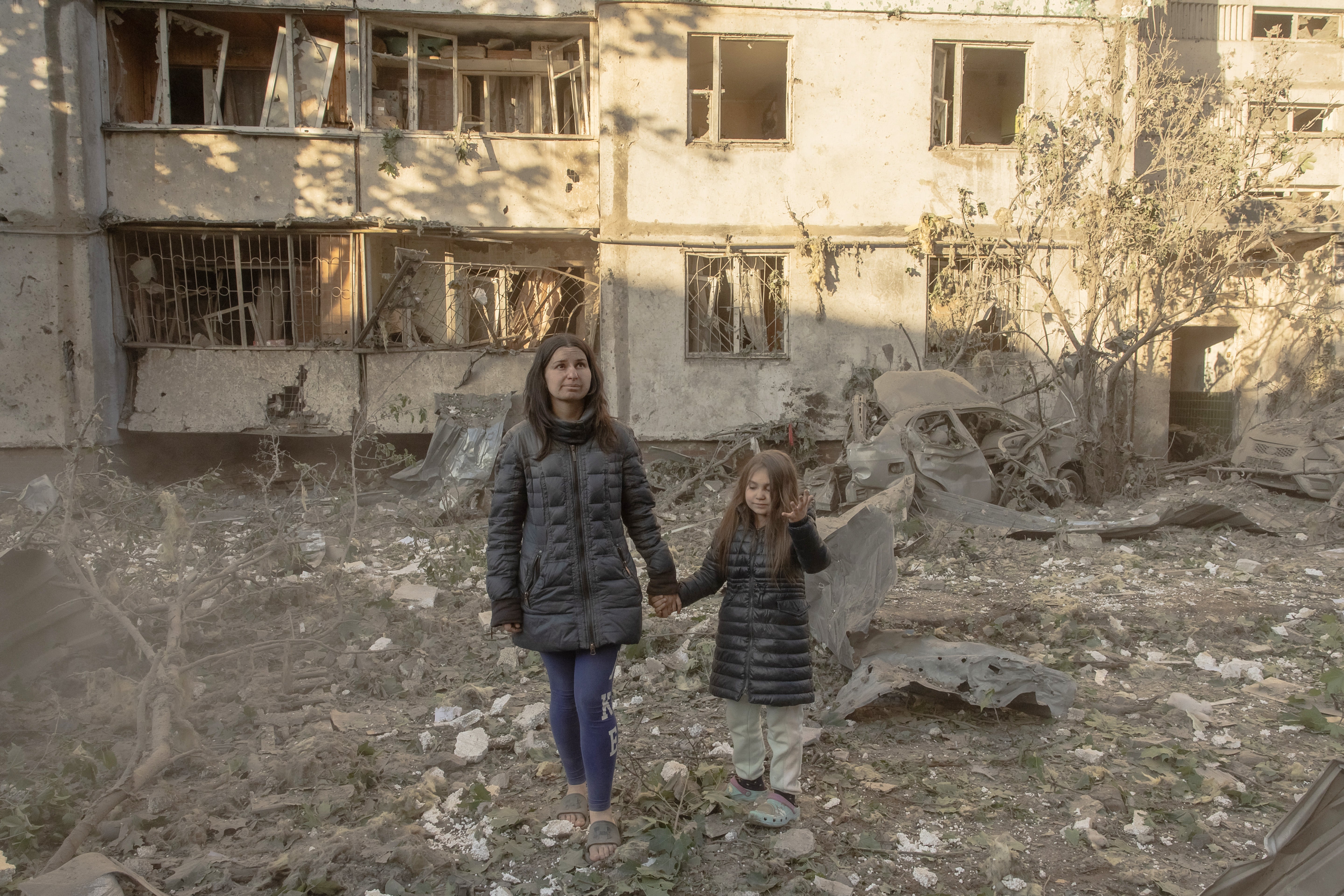 Olha Mudra walks with her six-year-old daughter, Nataliia, near the multi-storey residential building where they live, which was damaged during massive Russian missile and drone strikes on Kyiv (AFP/Getty)
