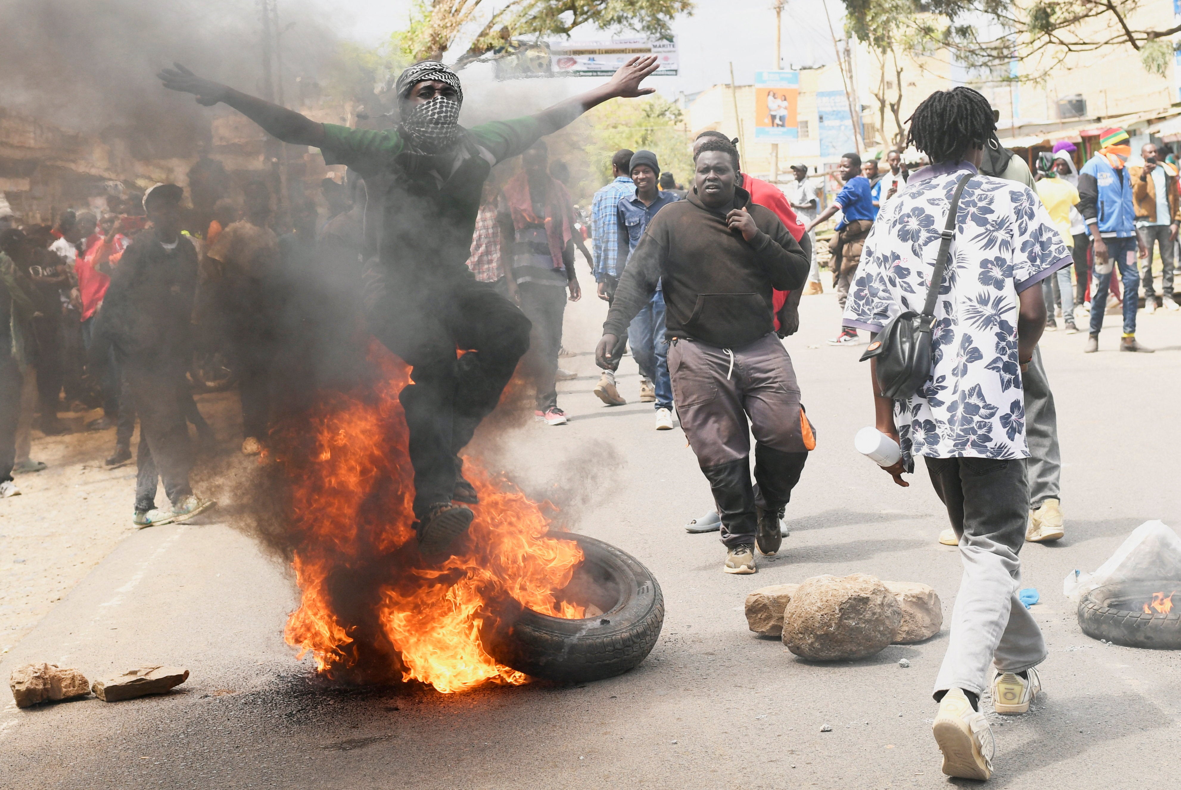 A demonstrator jumps over a barricade of burning tyres during a protest against a U.S.-backed Ebola quarantine plan on the establishment of a 50-bed facility at a Kenyan air force base that was intended to host Americans exposed to Ebola