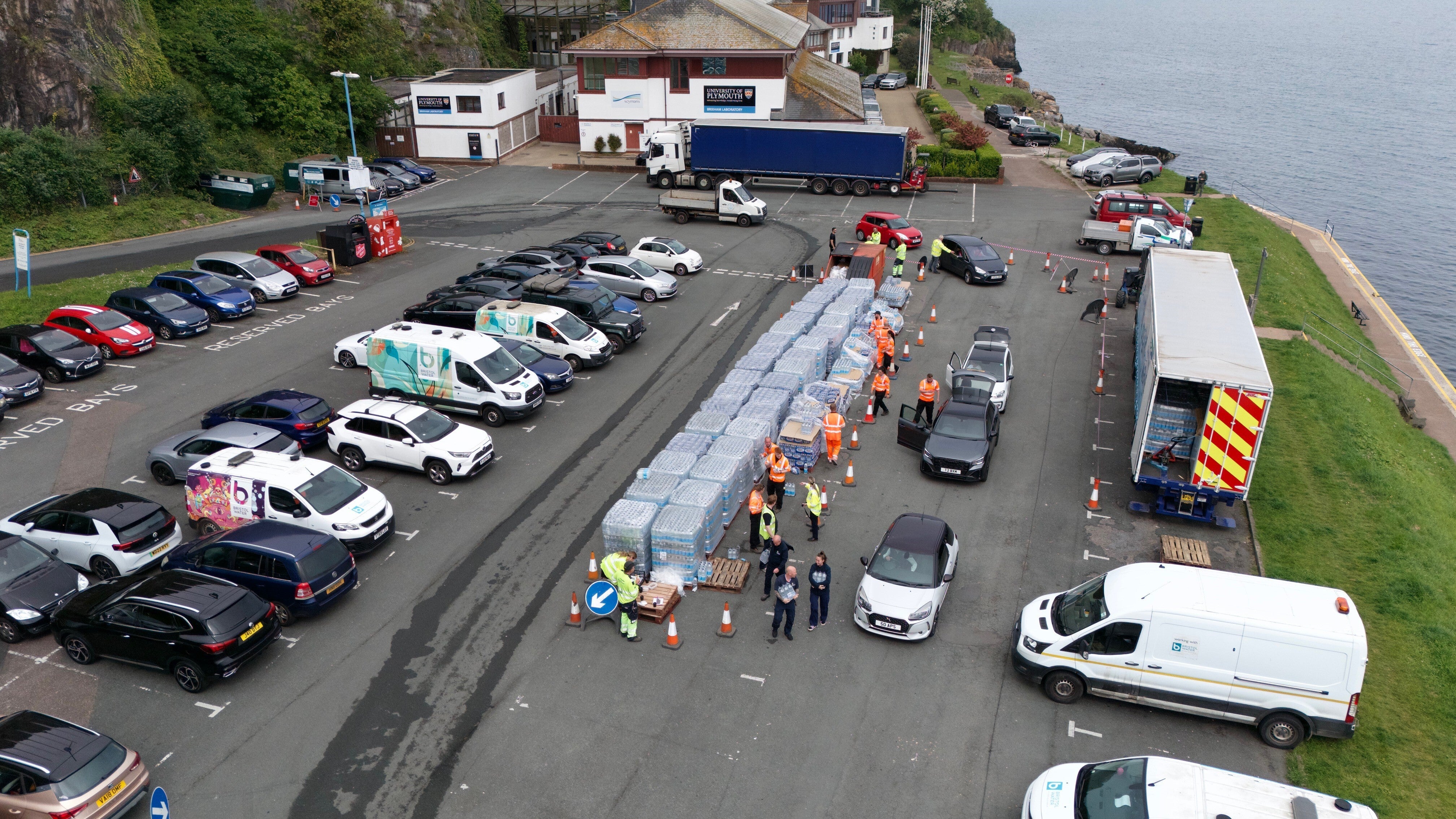 A drone view of people collecting bottled water at Freshwater car park in Brixham (PA)