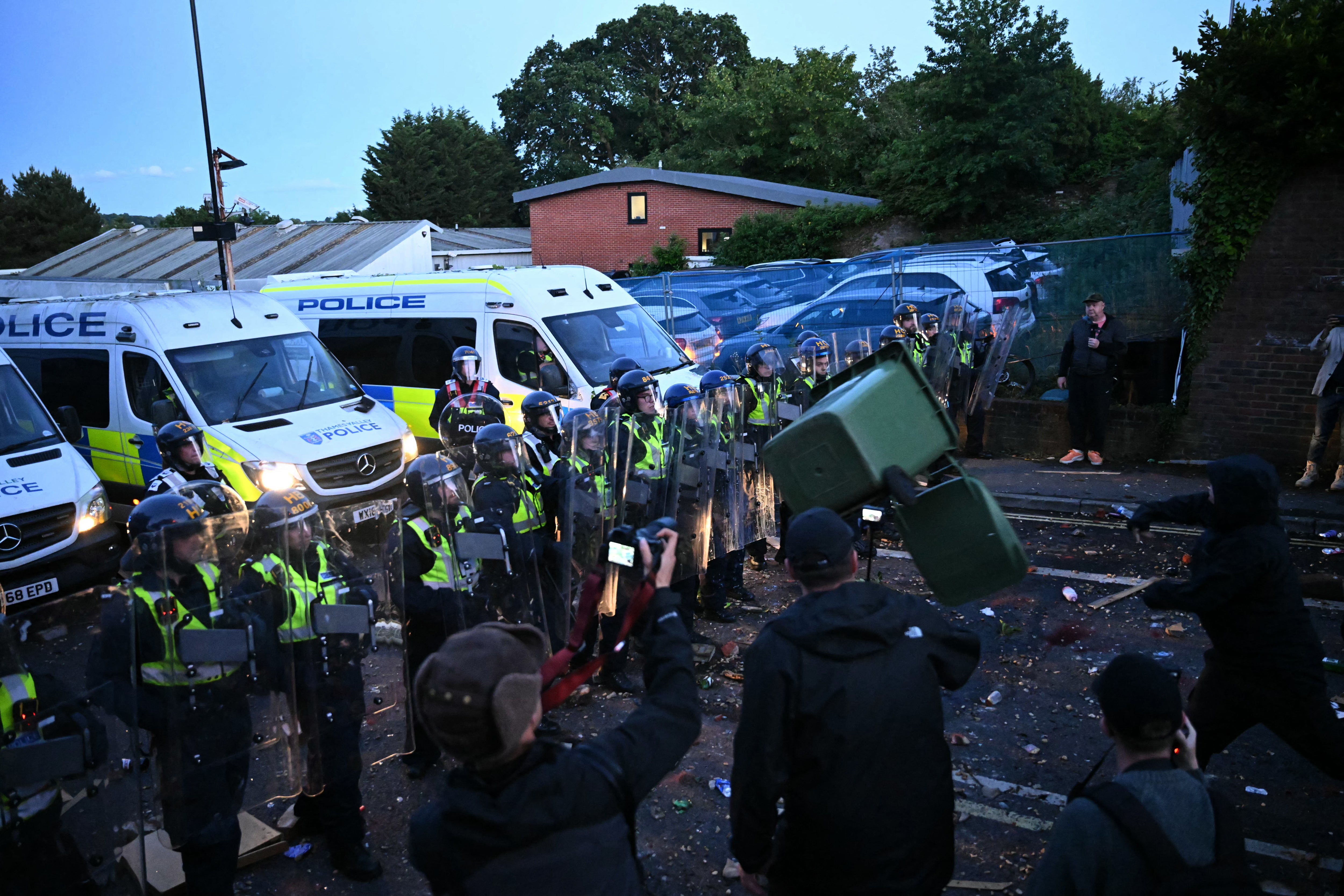 A demonstrator throws a bin at police offices with wheelie pins near Portswood Police Station