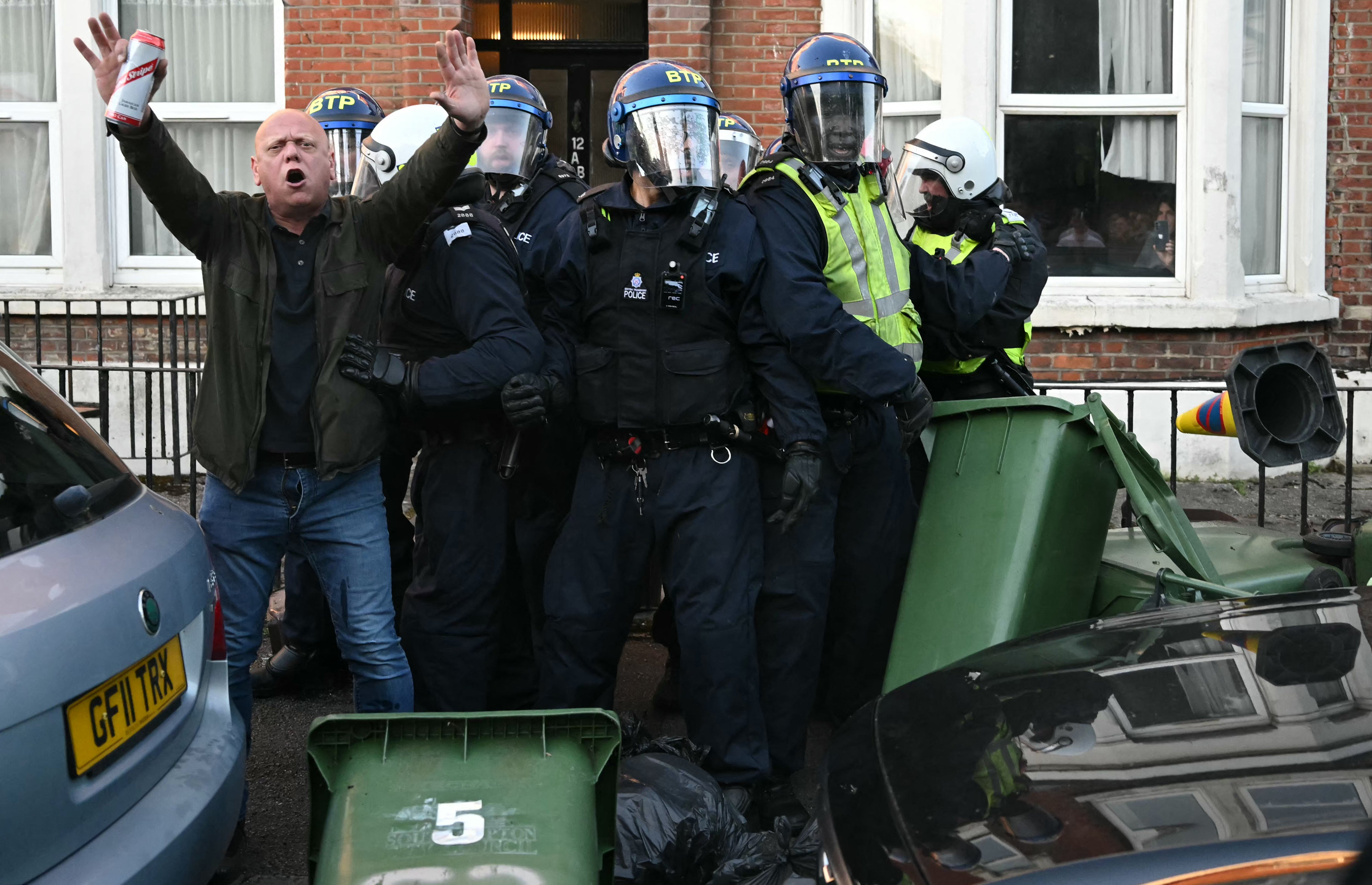 A person attempts to calm the crowd as Police officers are attacked by demonstrators near Portswood Police Station, following a protest march in Southampton