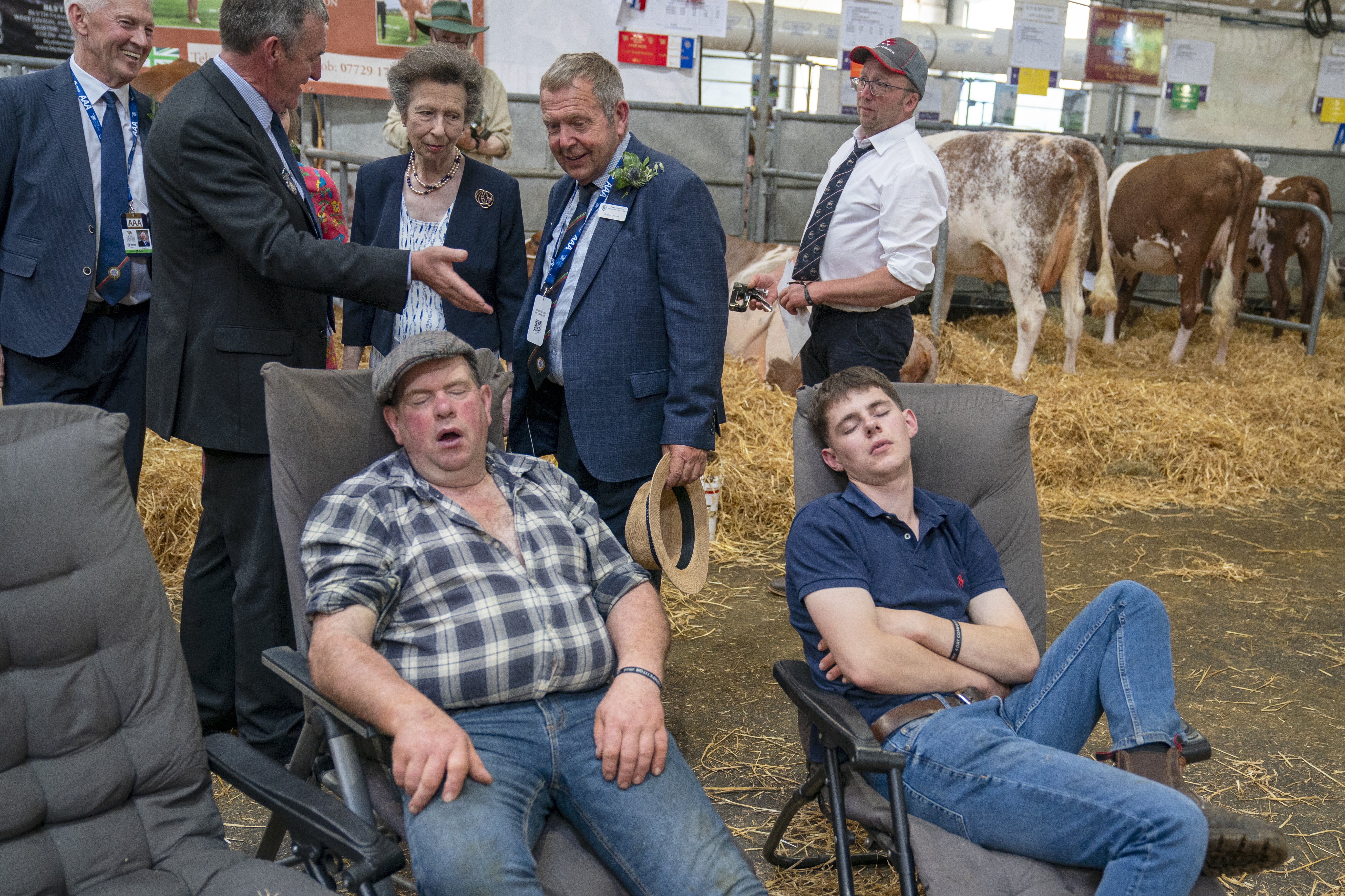 A couple of farmers sleep as the Princess Royal tours the cattle stalls in the Highland Hall during a visit to the Royal Highland Show at the Royal Highland Centre in Ingliston, Edinburgh (Jane Barlow/PA)