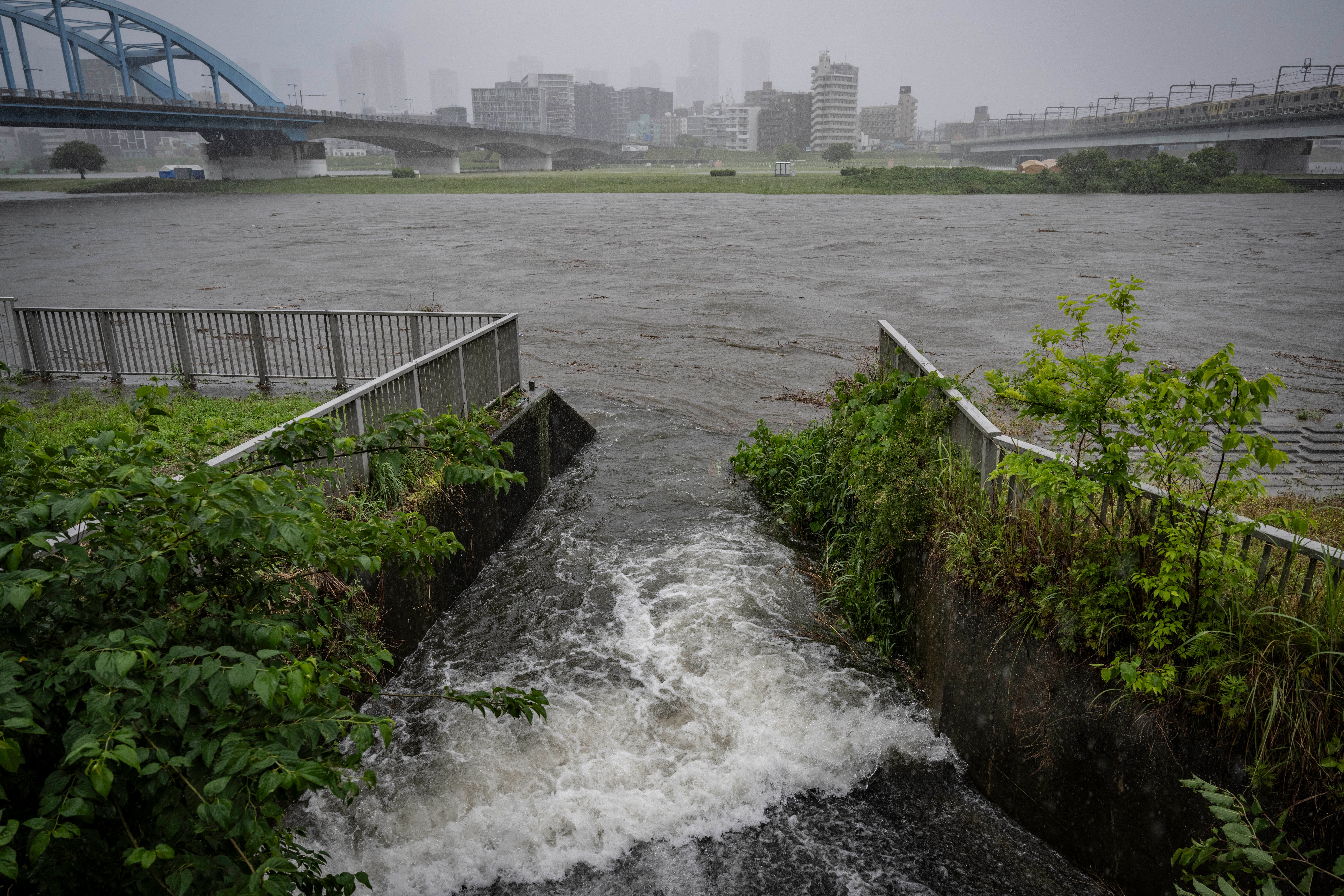 Water flows into the swollen Tama river amid heavy rain brought by severe tropical storm Jangmi in Tokyo on 3 June 2026 (AFP/Getty)