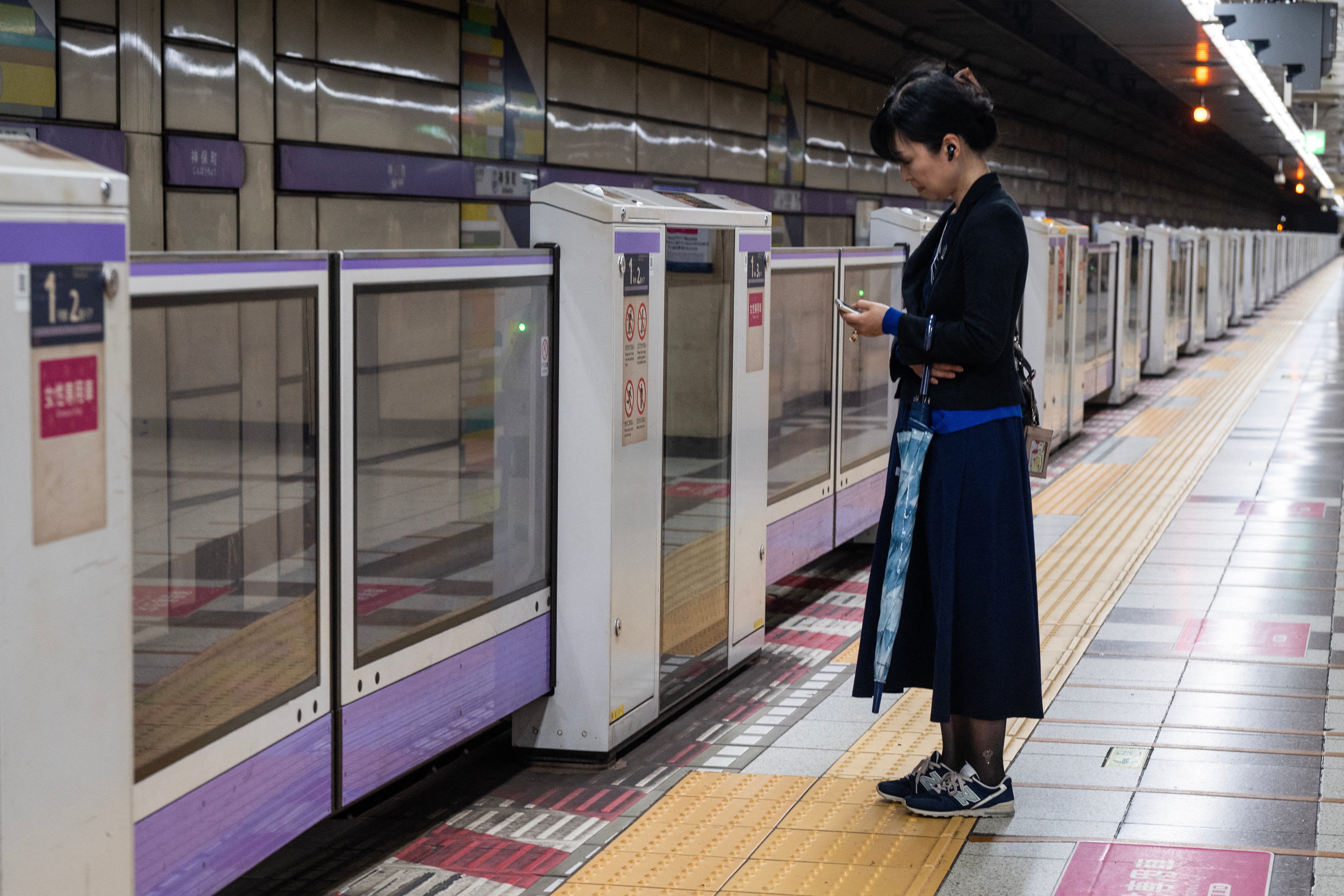 A woman holding her umbrella waits for a train on an empty platform at rush hour as severe tropical storm Jangmi passes over Tokyo on 3 June 2026 (AFP/Getty)