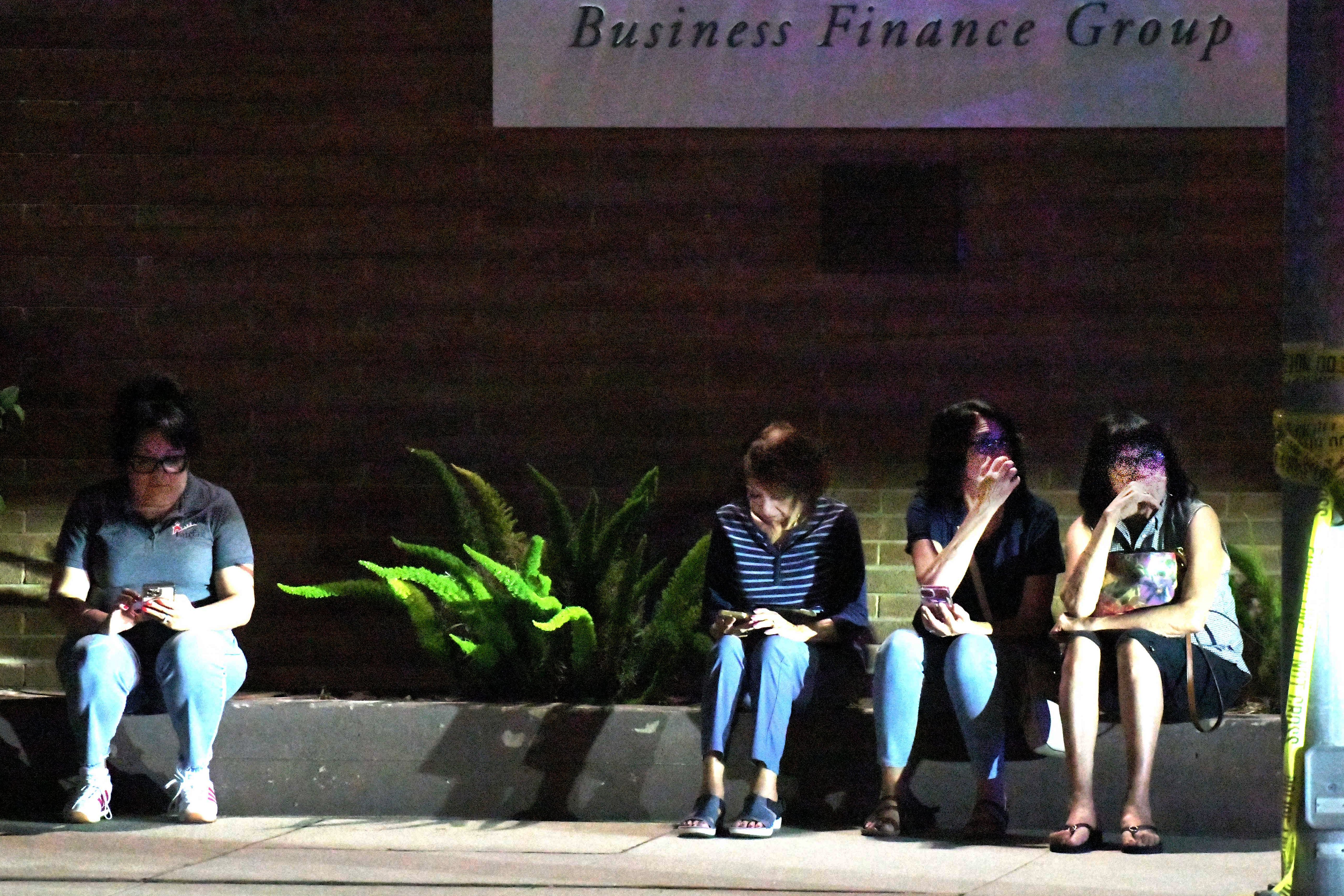 Family members of hostages wait a block away from a bank building where a man barricaded himself inside with hostages (AP)