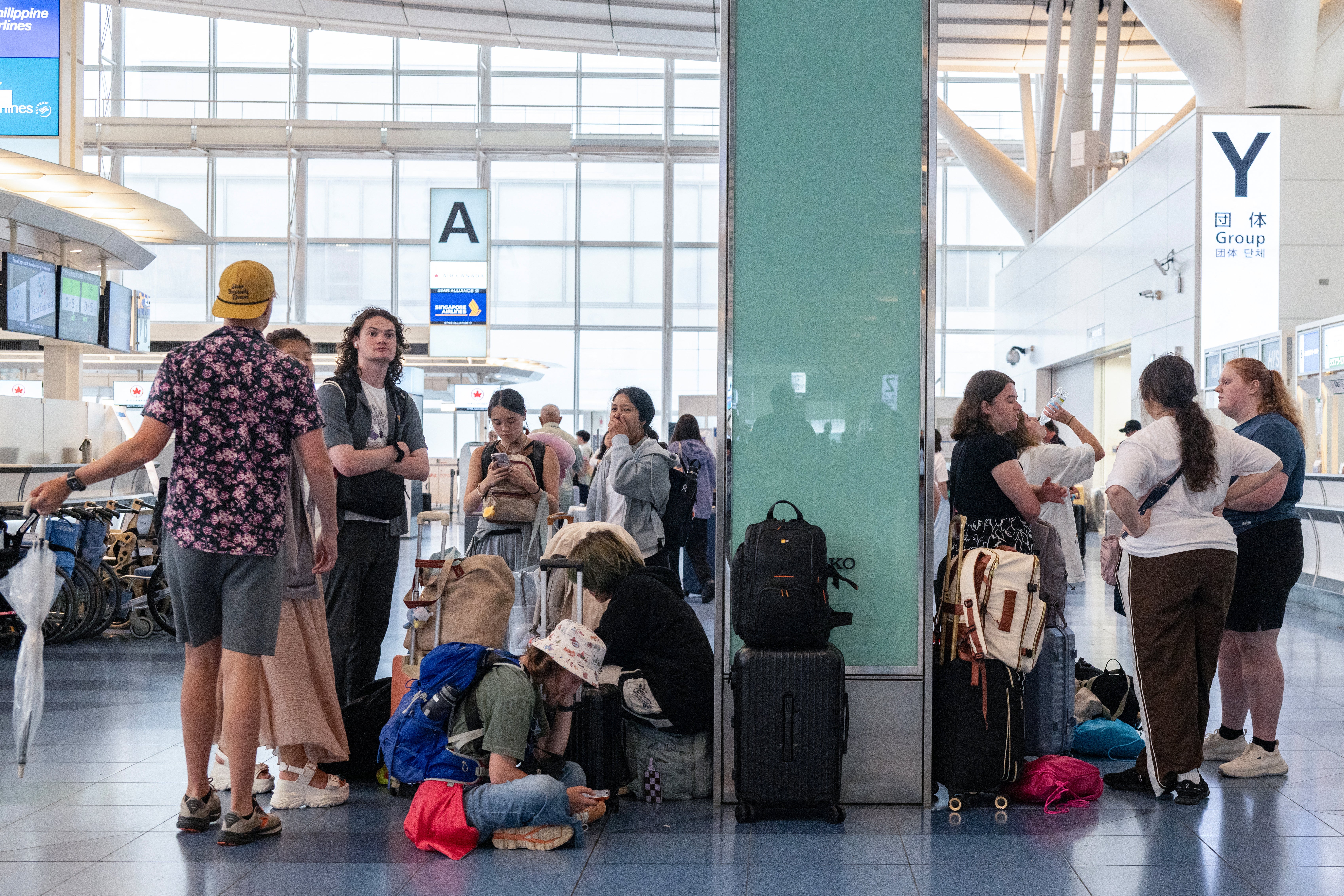 Passengers wait at the international terminal at Haneda airport after flights were cancelled or severely delayed because of severe tropical storm Jangmi in Tokyo on 3 June 2026 (AFP/Getty)