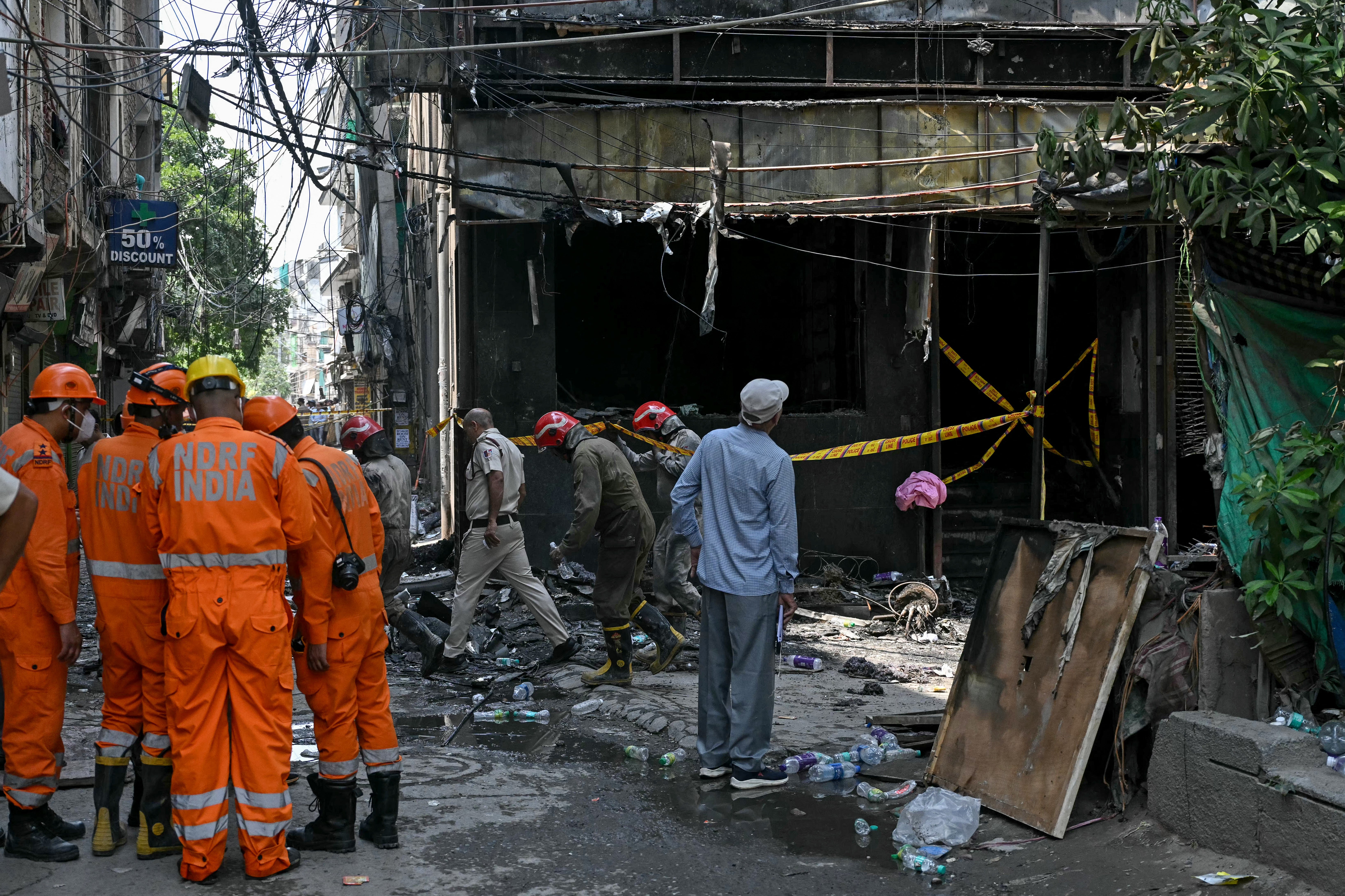 National Disaster Response Force (NDRF) personnel and firefighters stand at the site following a fire that broke out at a hotel in New Delhi on June (AFP/Getty)