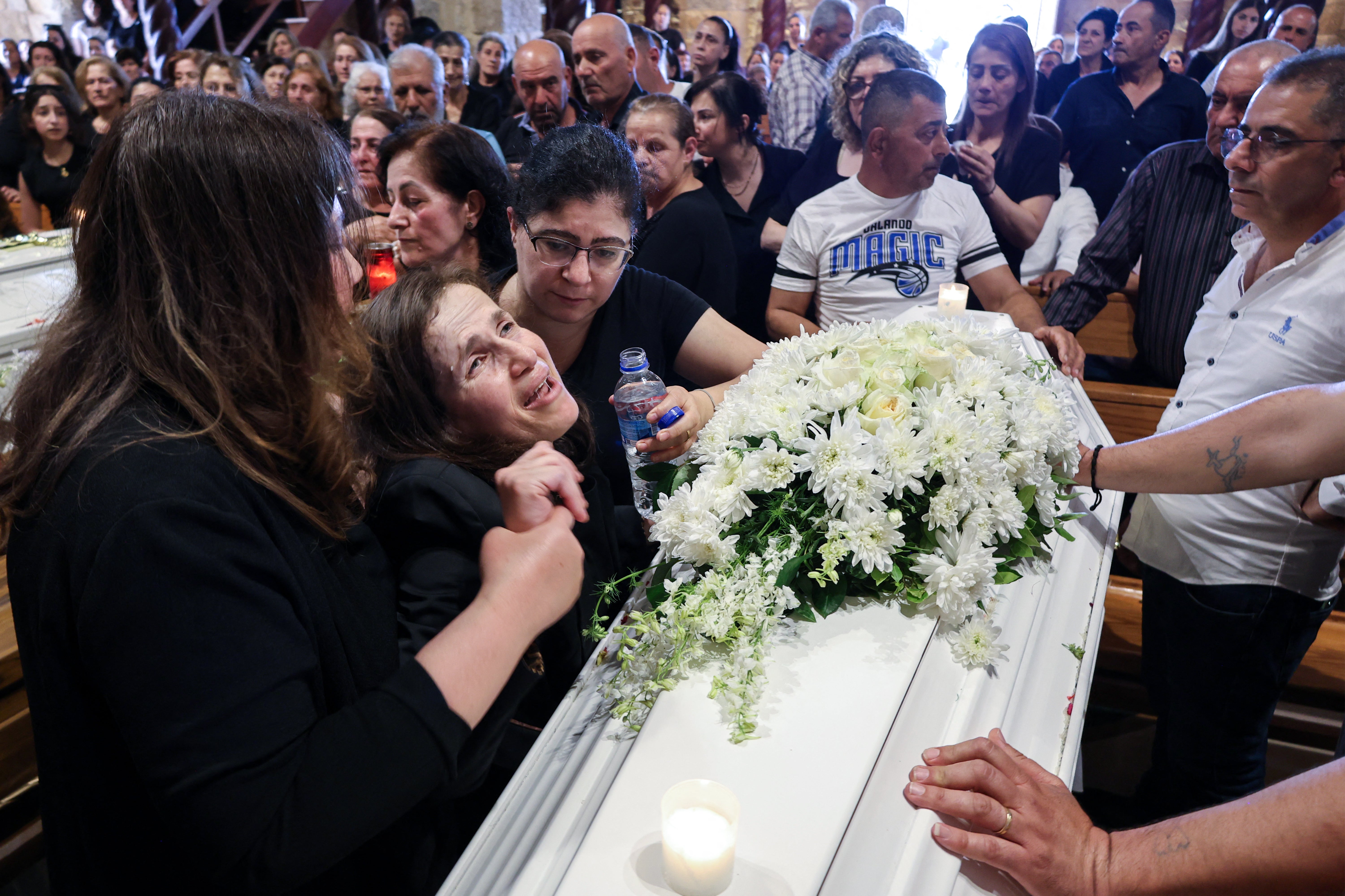 A relative of a man who was killed along with his son and daughter in an Israeli strike that targeted their car earlier this week in southern Lebanon reacts as she mourns over their coffins during their funeral in the christian border village of Qlayaa (AFP/Getty)