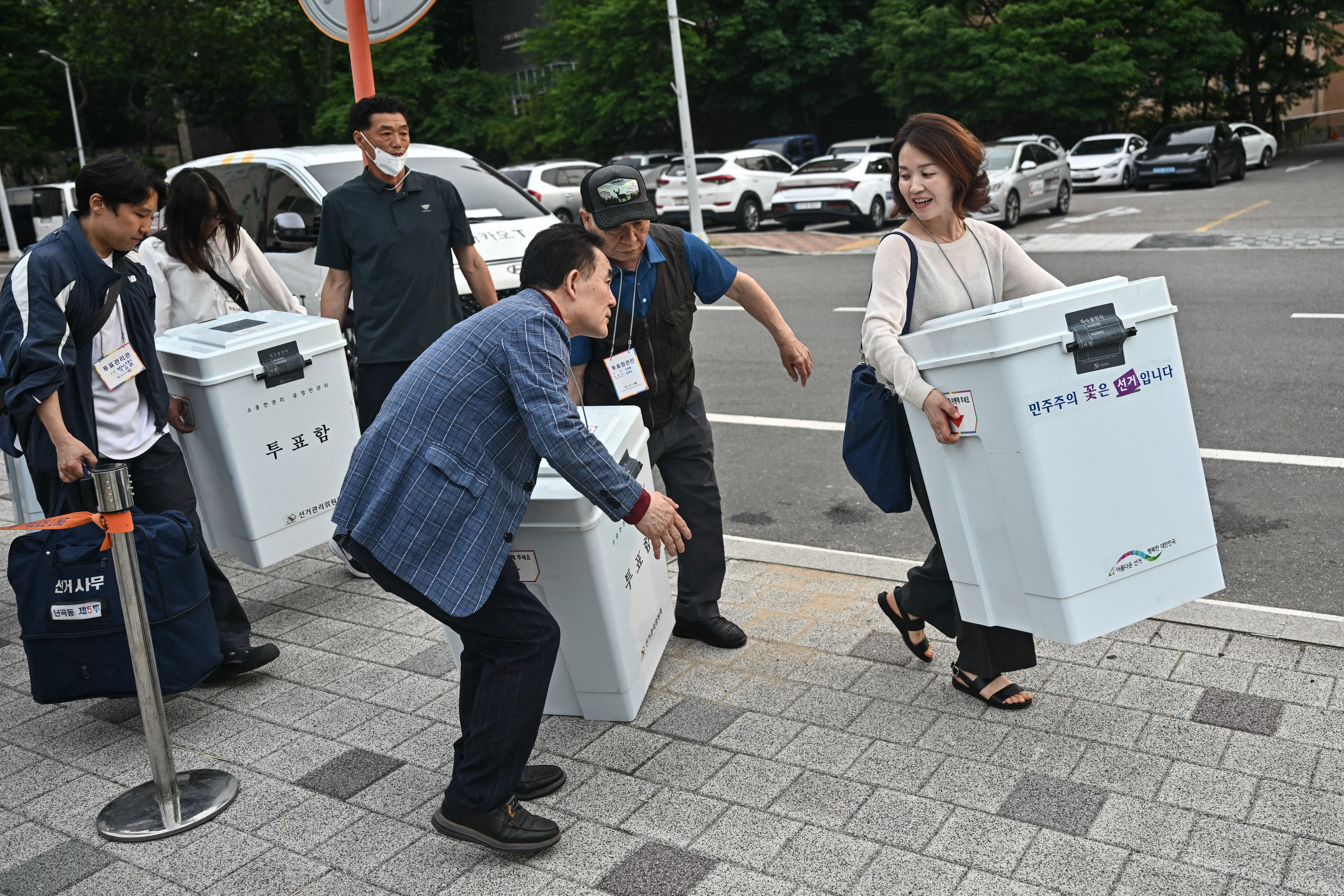 Election officials carry ballot boxes outside a counting station for local elections in Seoul on 3 June 2026