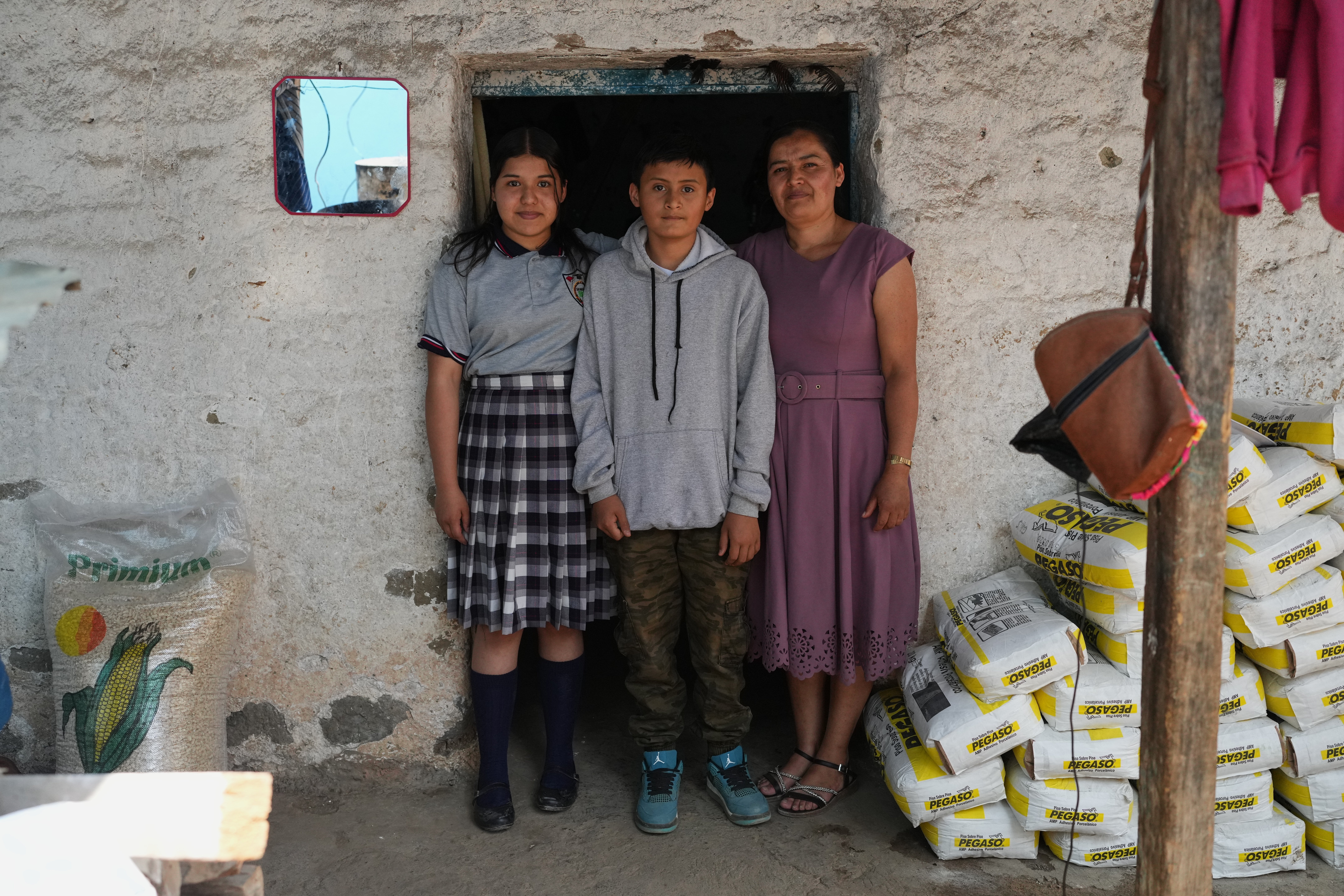 Alva López, right, and her children, Ederson, center, and Briseidy pose for photos at their house in San Martín Cuchumatán