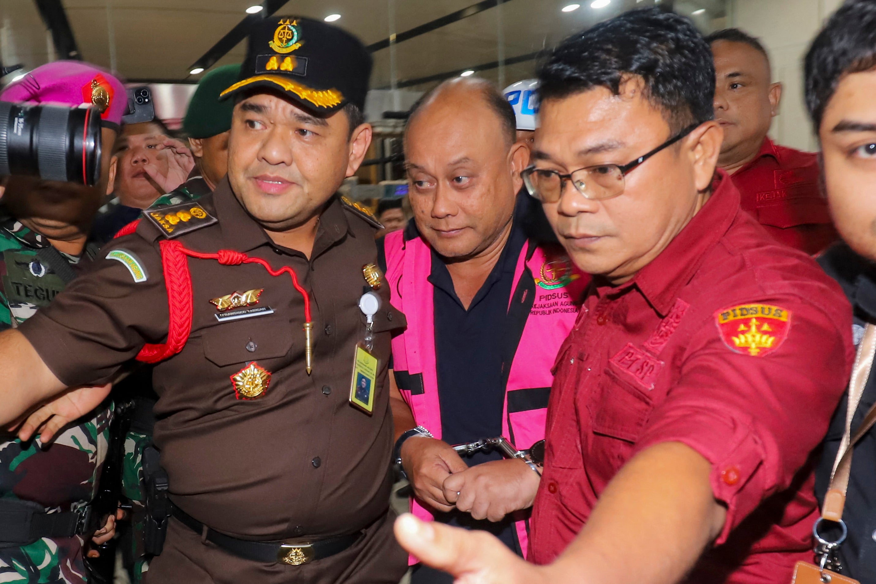 Dadan Hindayana (C), former head of Indonesia's free school meals programme, is escorted by officers from the Attorney General's Office and Indonesian military personnel as he leaves the Attorney General's Office building in Jakarta on 3 June 2026, following questioning over alleged misappropriation in the implementation of the programme