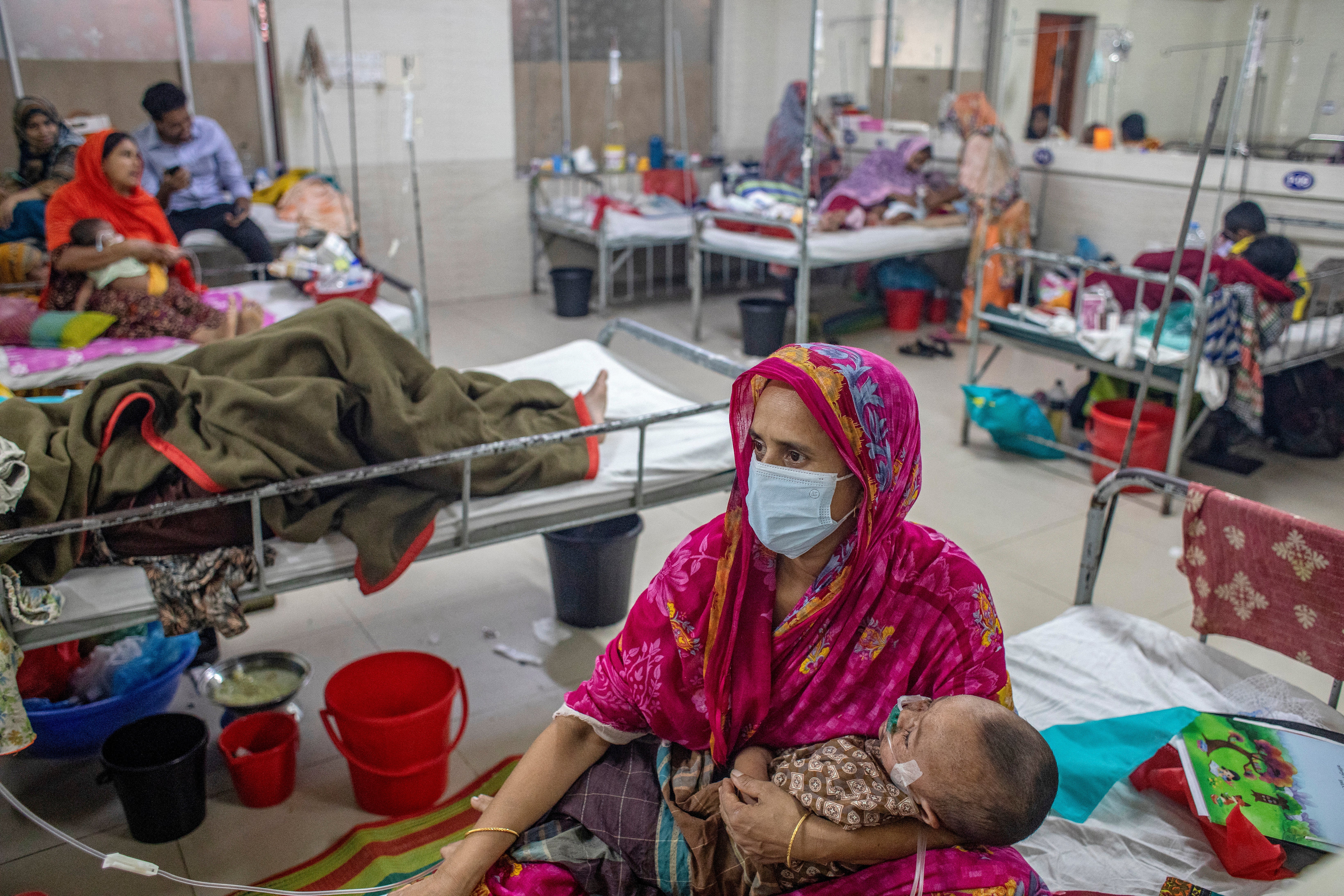 A woman holds a child diagnosed with measles inside the Bangladesh Shishu Hospital and Institute in Dhaka on 6 May 2026 (AFP/Getty)