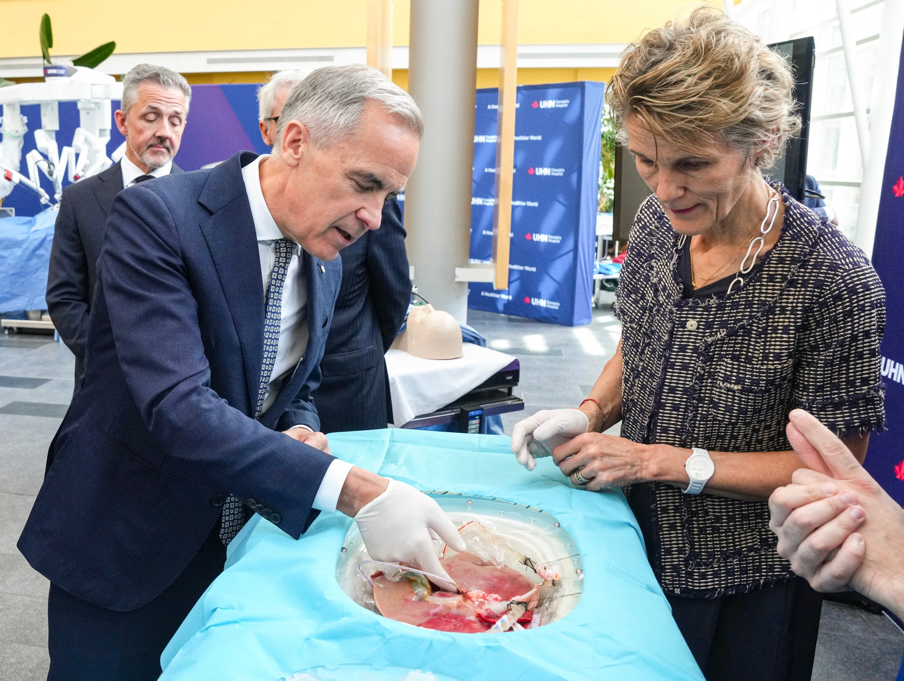 Prime Minister Mark Carney and his wife Diana Fox Carney inspects a pig's lungs during an AI demonstration as they visit Toronto General Hospital on Thursday, June 4 2026 (The Canadian Press)
