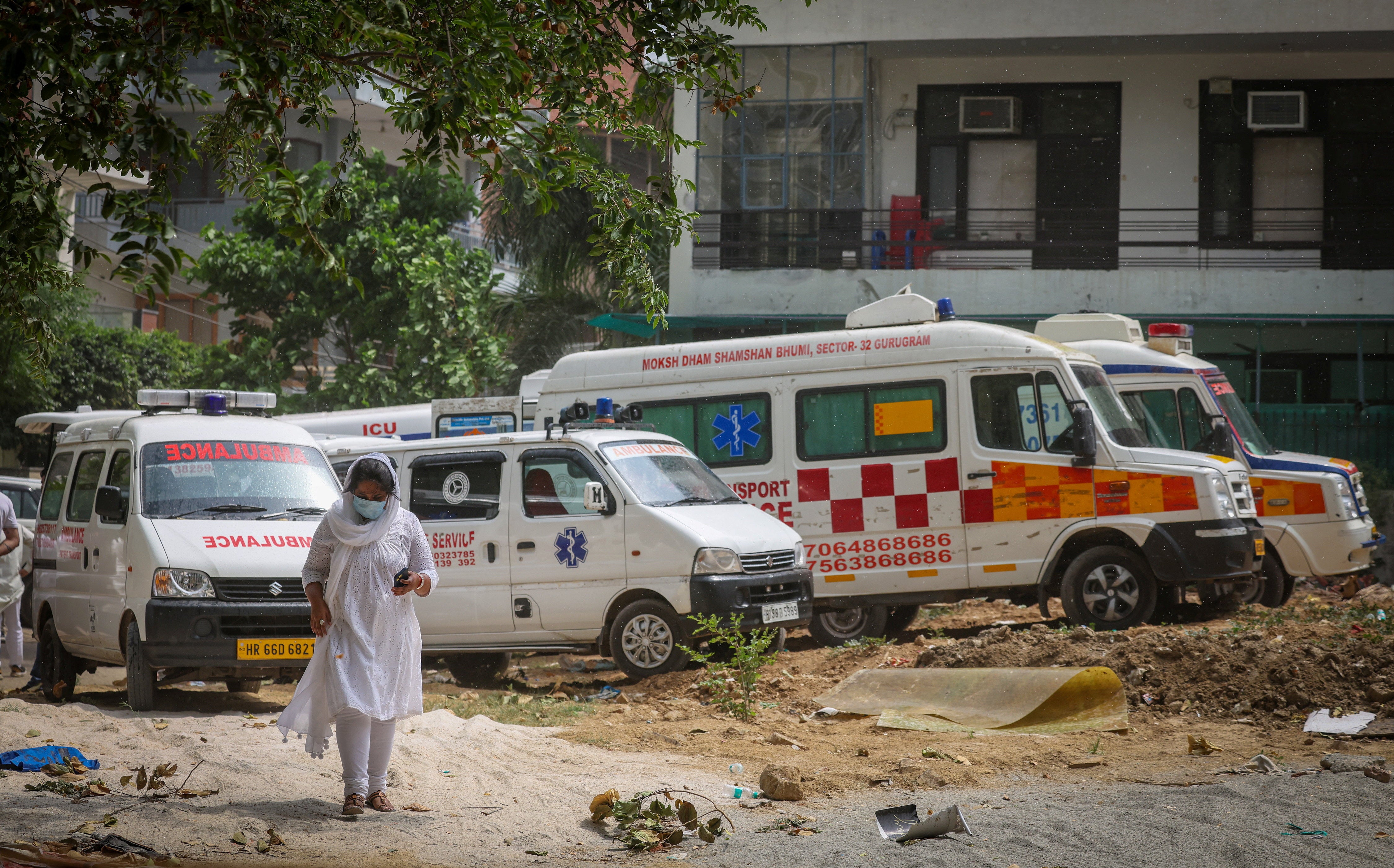 A woman walks past ambulances carrying the remains of Vivek Aggarwal and his family, who died in a fire at a hotel in Delhi on Wednesday, on 4 June 2026