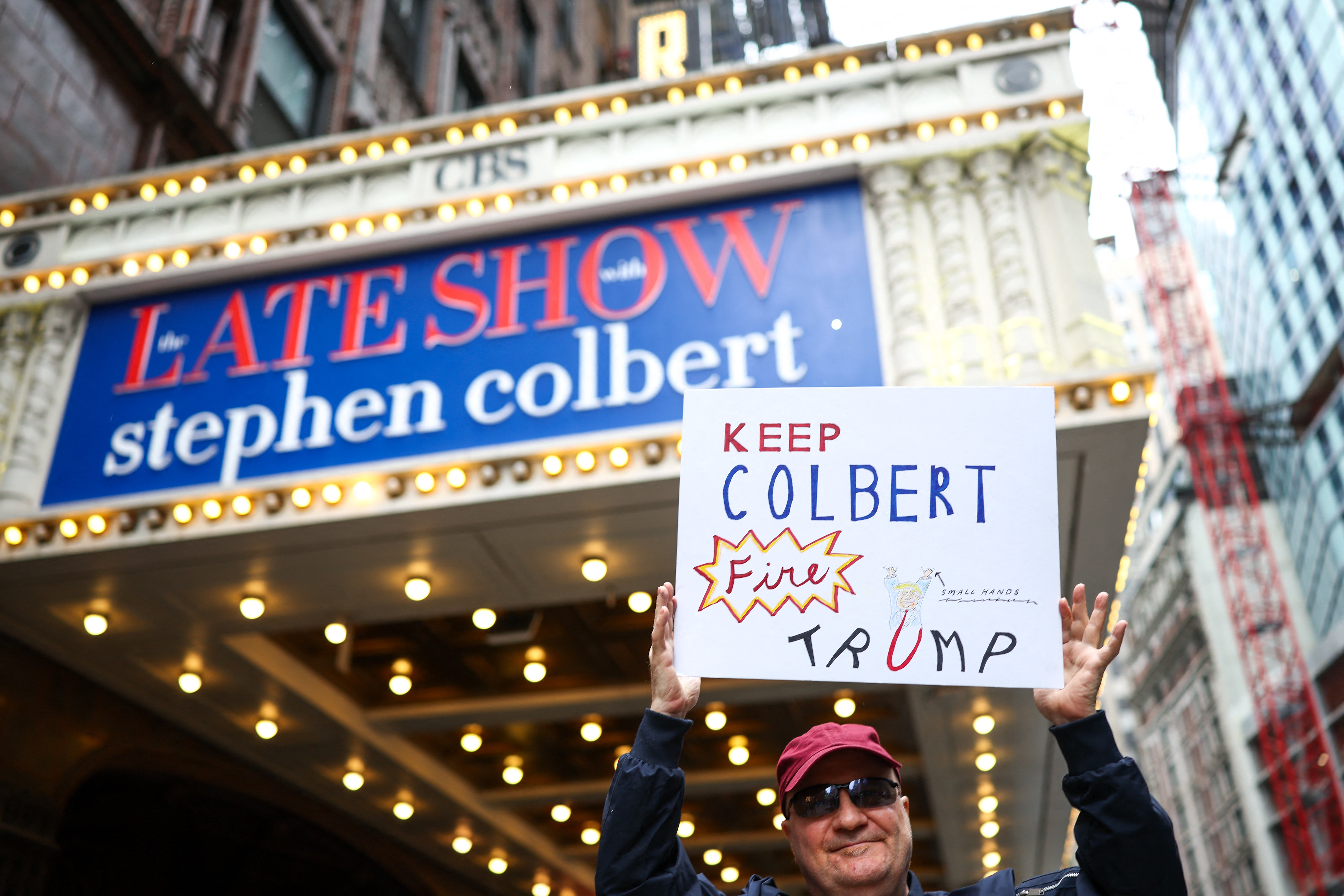 A man holds a sign outside the Ed Sullivan Theater ahead of the taping of the final episode of the 