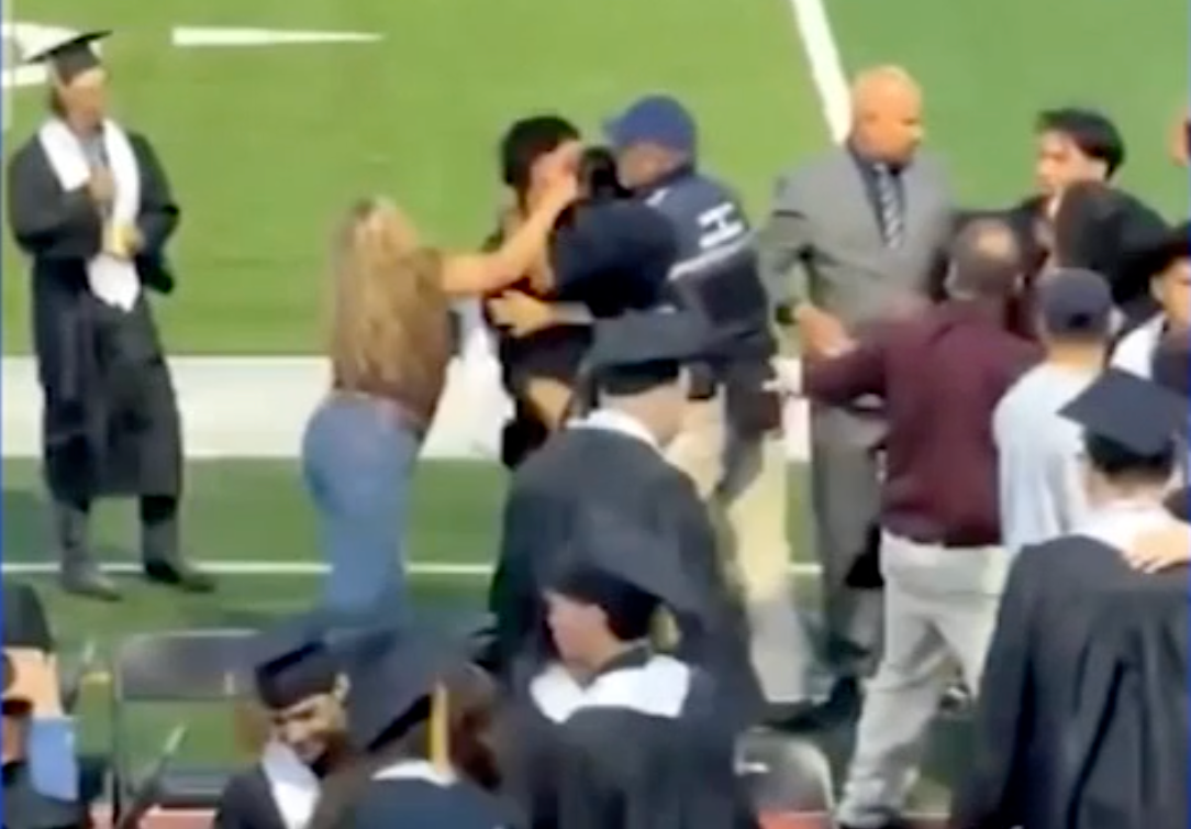 A woman in a brown shirt was recorded throwing a punch, losing her balance and falling over