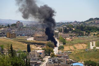 Black smoke billows at a strike scene following an Israeli strike on a car as seen from Nabatieh, Lebanon