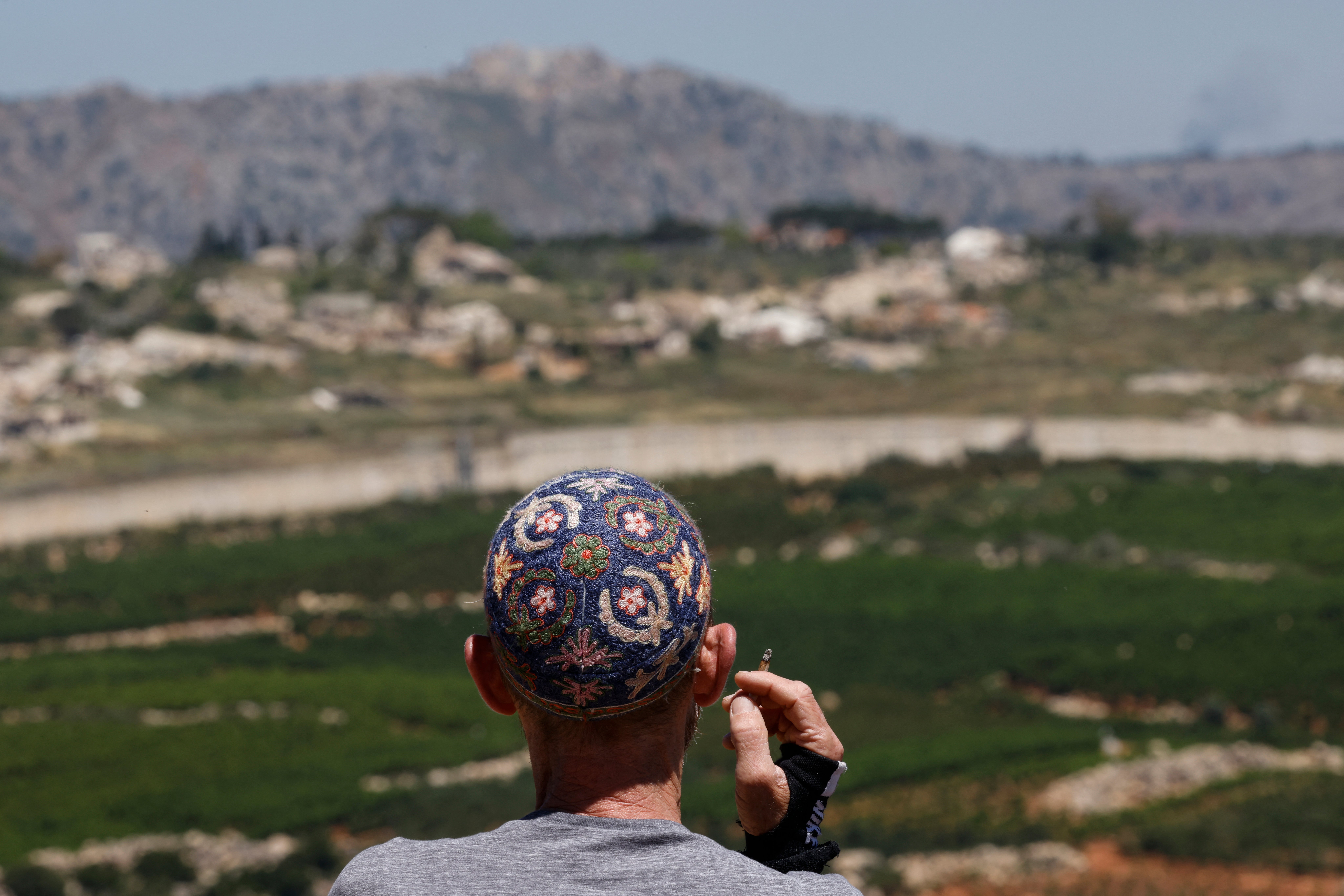 An Israeli man stands against the backdrop of southern Lebanon, along the Israel-Lebanon border