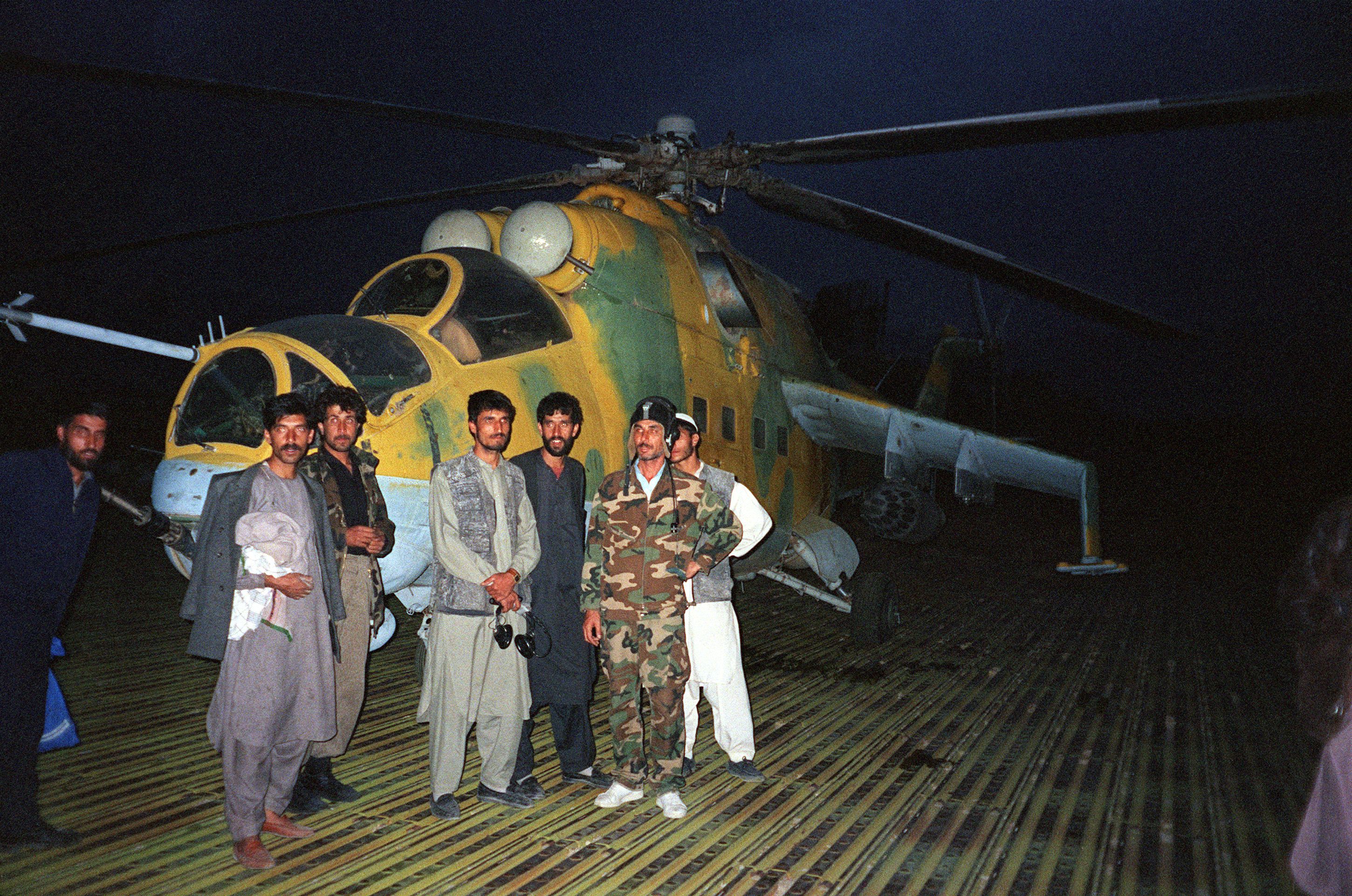 Taliban forces pose in front of a Soviet-made MI-24 helicopter gunship at Bagram military air base in 1996 (AFP/Getty)