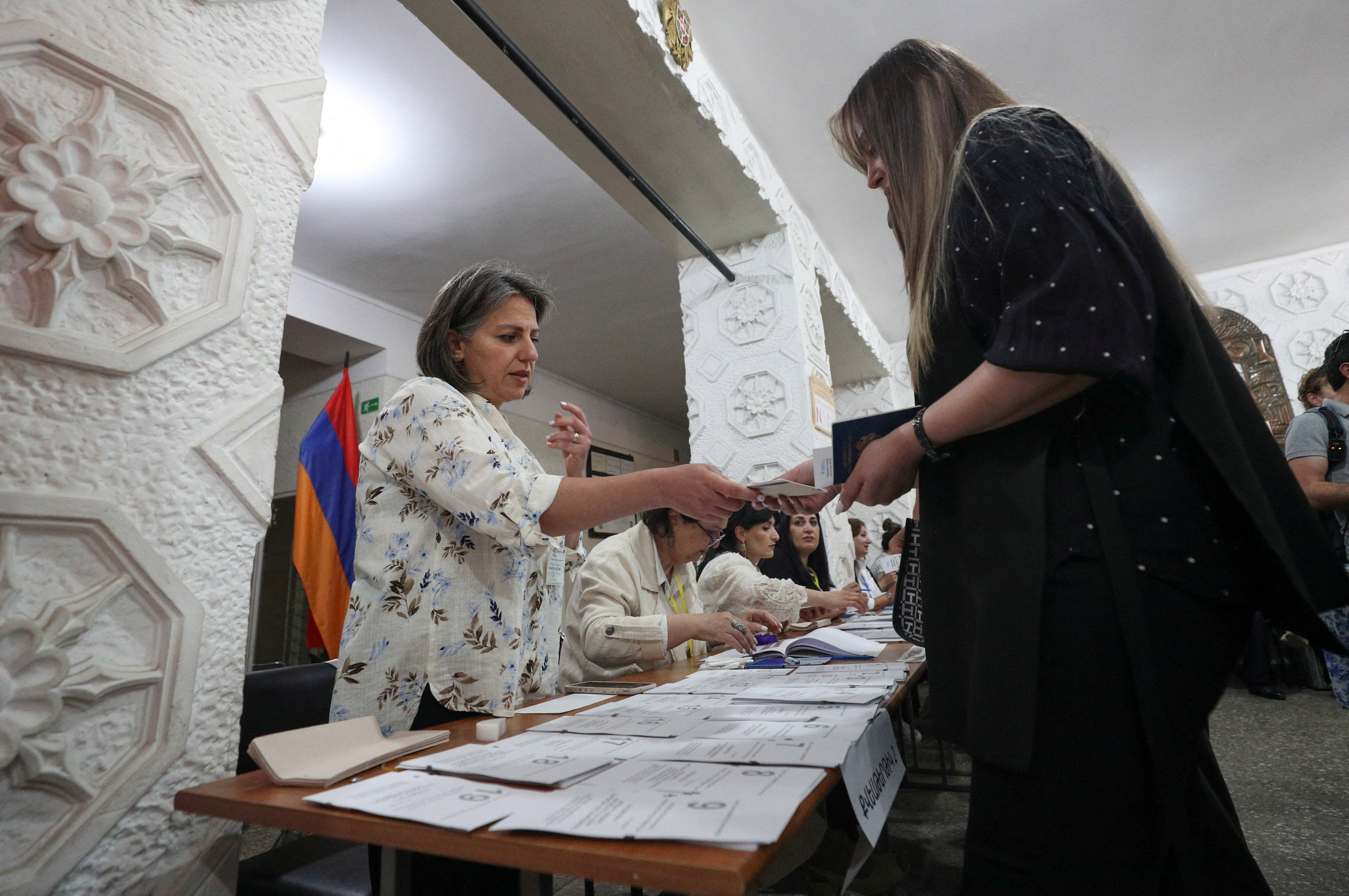A voter receives a ballot from an official at a polling station during a parliamentary election in Yerevan, Armenia (Reuters)