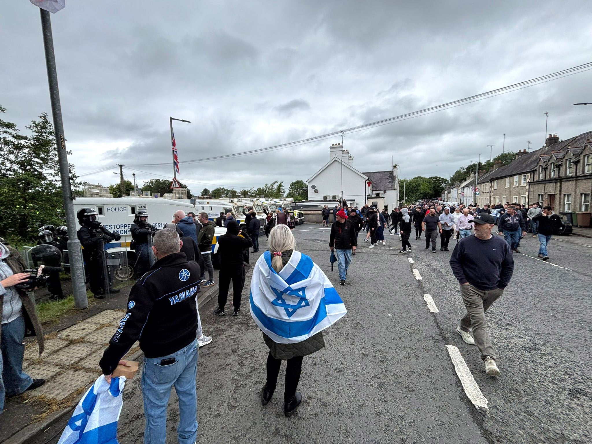 PSNI officers in riot gear with armoured vans separate counter protesters as the pro-Palestinian march from Lurgan to Newry passes through the village of Scarva (Niall Carson/PA) (PA Wire)