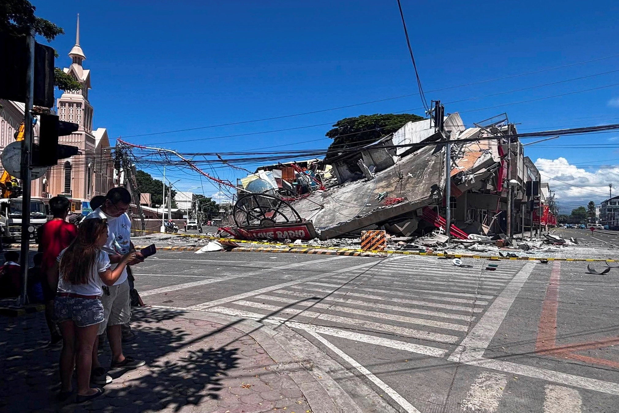 People stand near a collapsed building after a magnitude 7.8 quake in General Santos (Reuters)