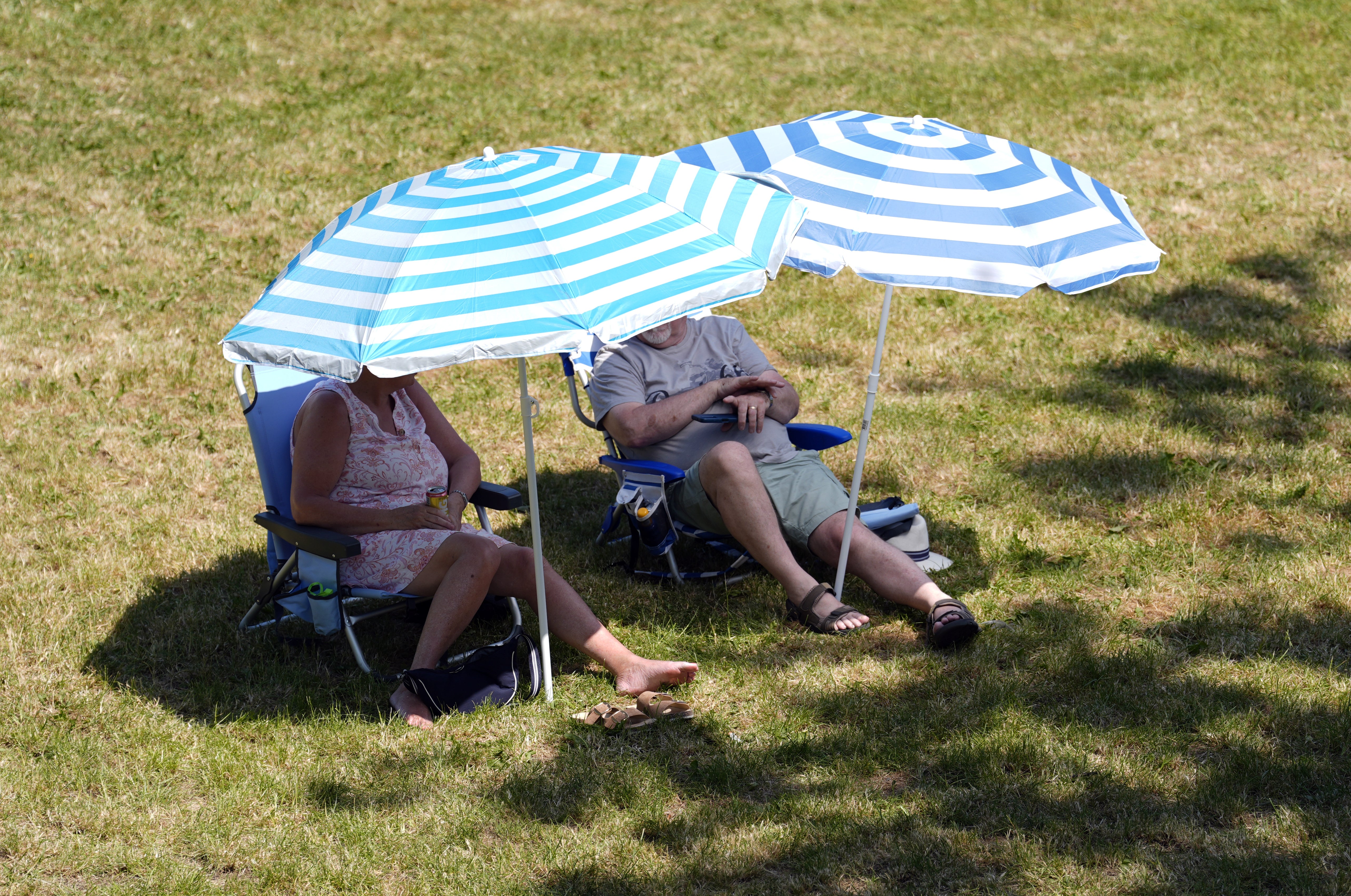 People shelter under parasols in Wallingford, Oxfordshire (Andrew Matthews/PA)