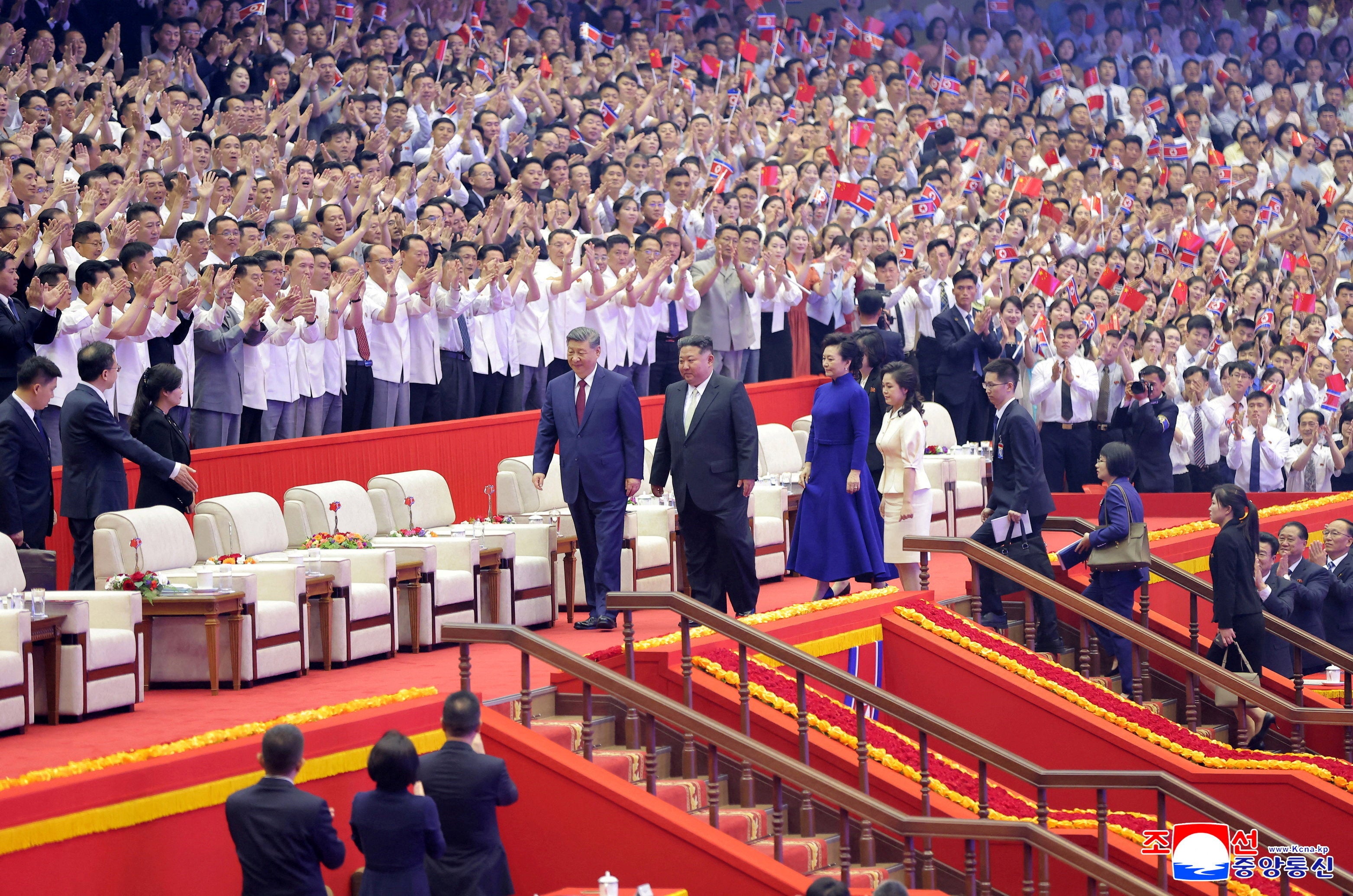 Chinese President Xi Jinping, his wife Peng Liyuan, North Korean leader Kim Jong Un, and his wife Ri Sol Ju walk together as they attend a performance at the Pyongyang Indoor Stadium, during Xi's state visit, in Pyongyang