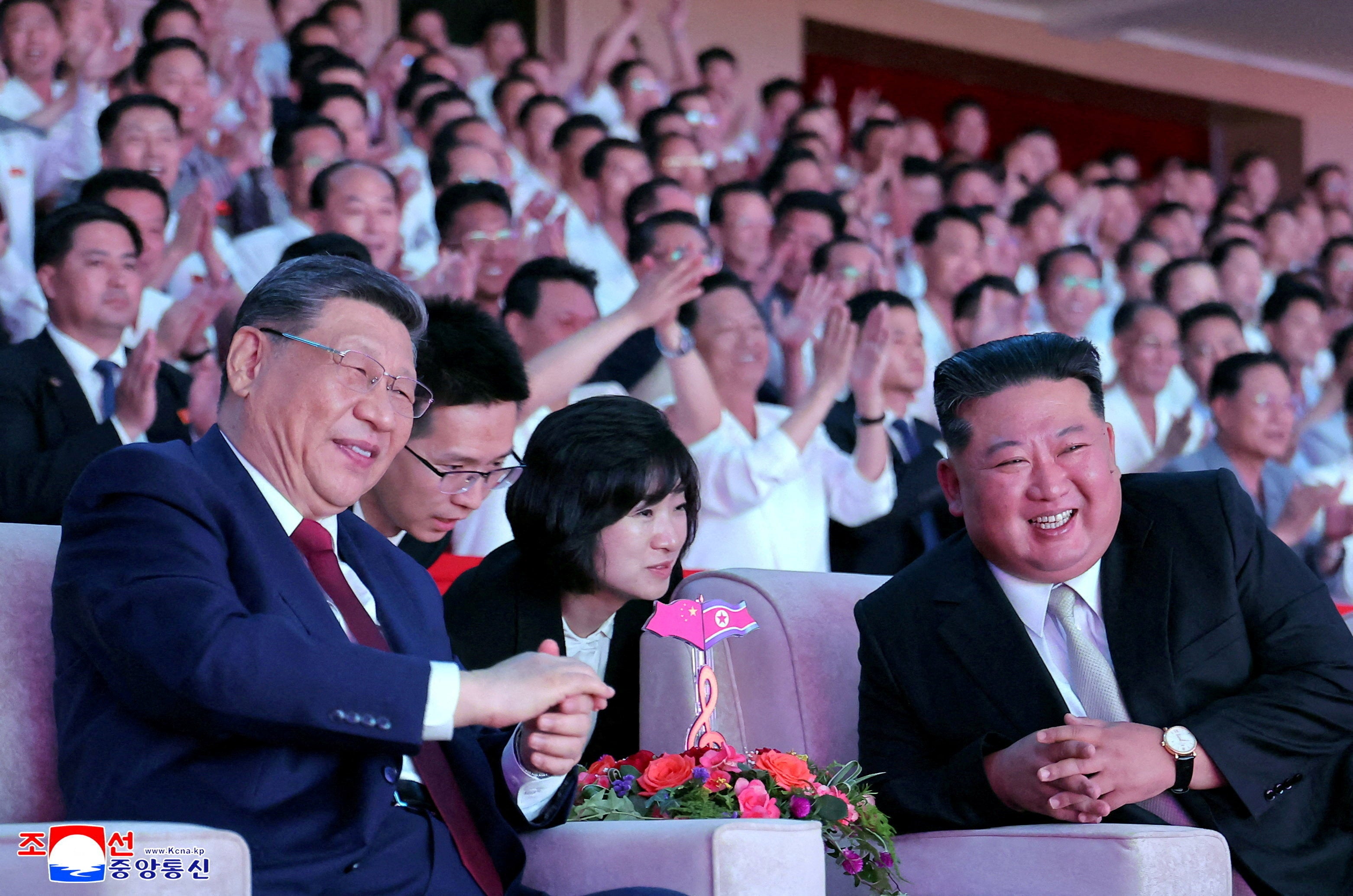 Chinese President Xi Jinping sits next to North Korean leader Kim Jong Un as he attends a performance at the Pyongyang Indoor Stadium, during his state visit, in Pyongyang, North Korea