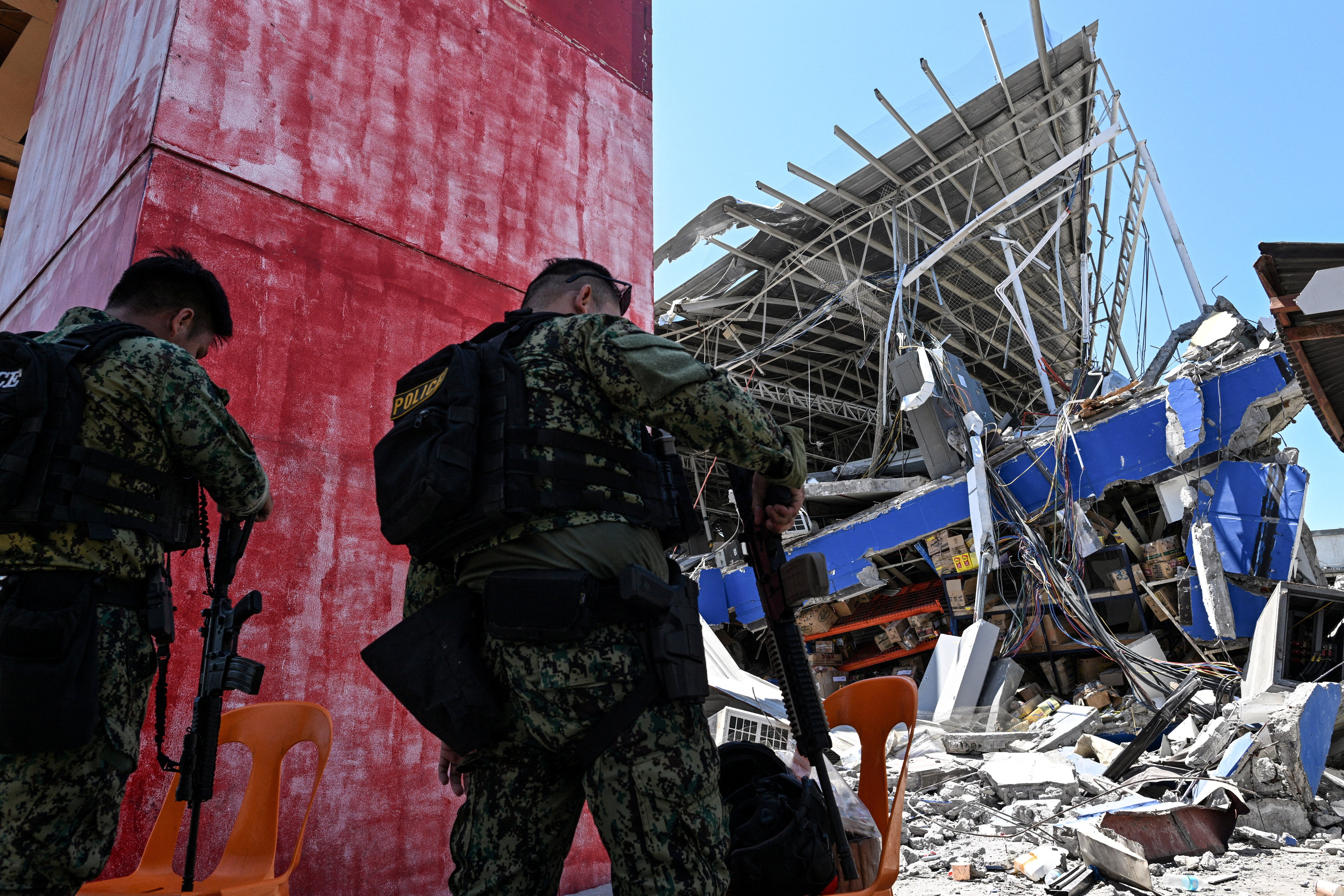 Policemen secure a collapsed grocery store a day after a powerful earthquake struck Calumpang, General Santos, Philippines