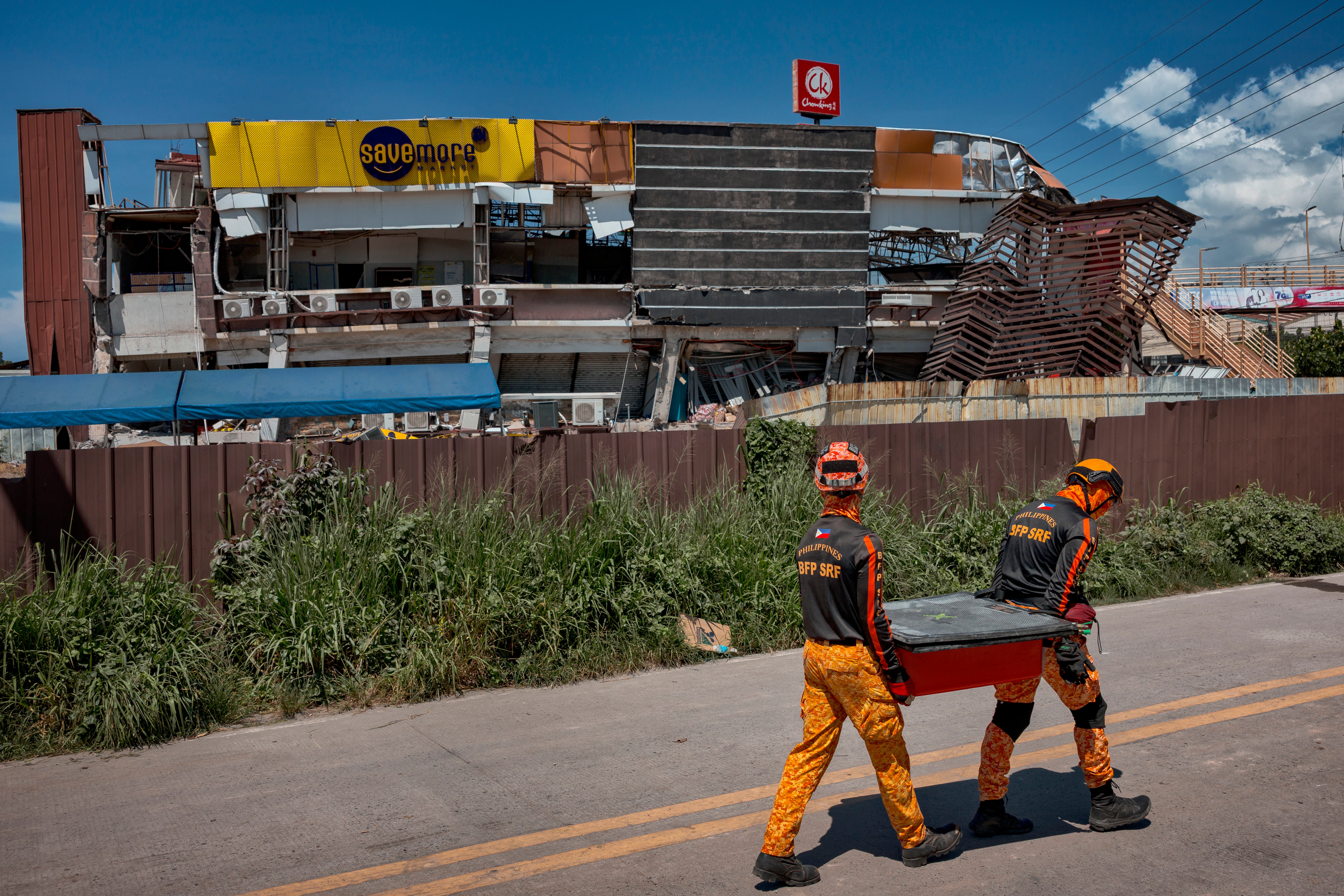 Rescue workers carry equipment near a building damaged by the earthquake in General Santos, Philippines, on 9 June 2026
