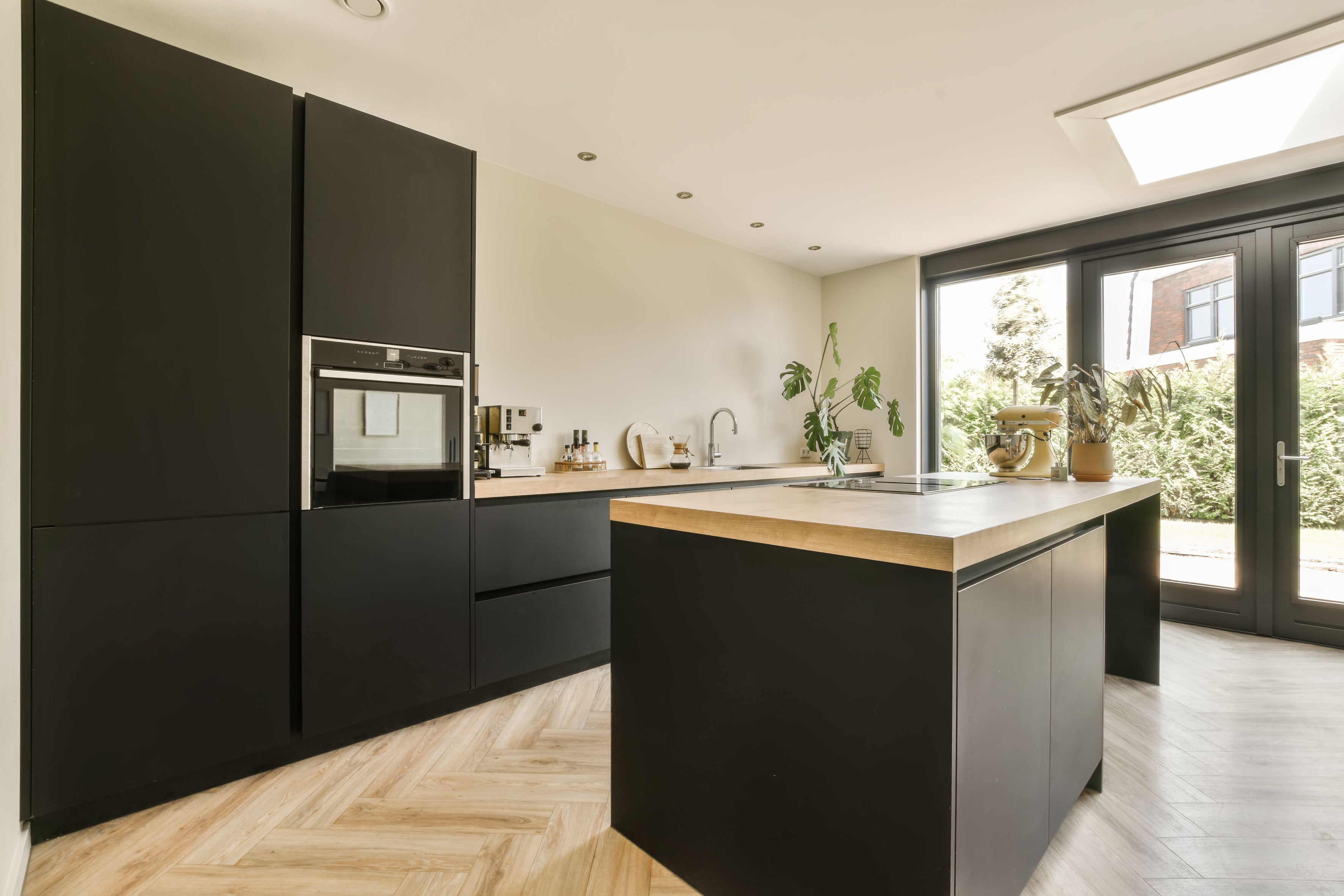 A modern kitchen with black cabinetry and wood flooring (Alamy/PA)