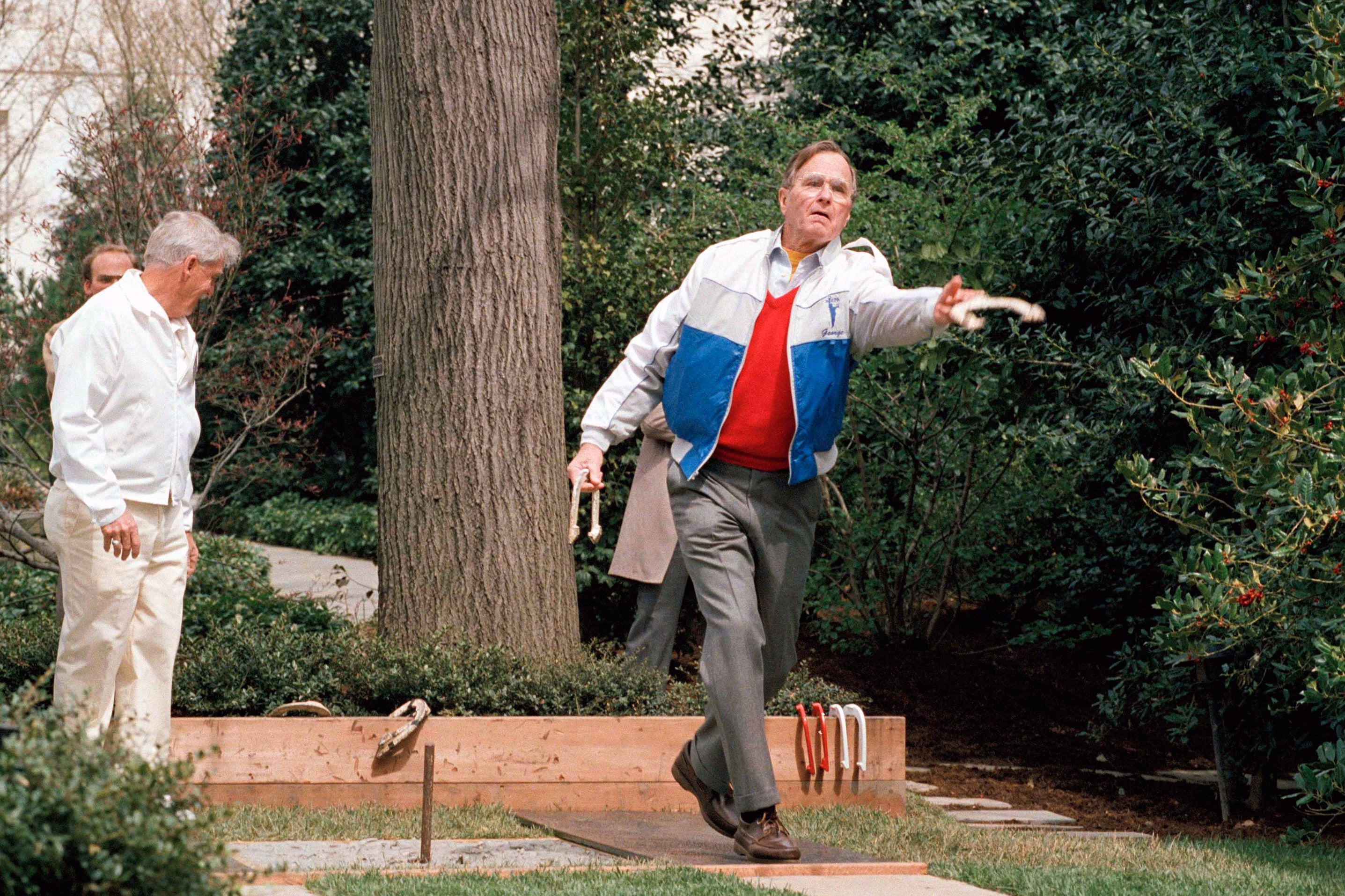 President George H.W. Bush lets loose of a horseshoe during the dedication of the new horseshoe pit on the White House lawn Saturday April 1, 1989 (AP Photo/Barry Thumma)