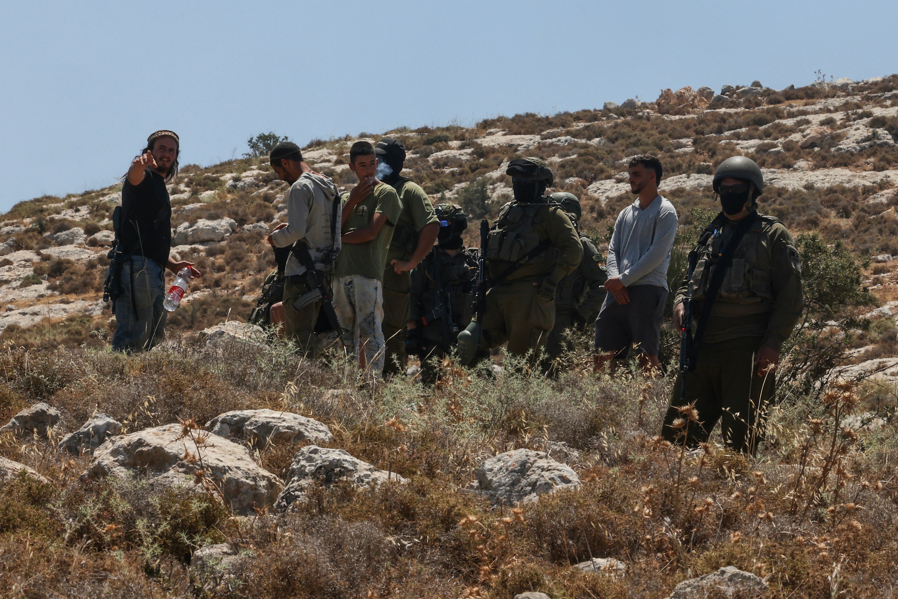 Israeli forces and armed settlers guard a bulldozer reportedly operating on Palestinian lands on 9 June