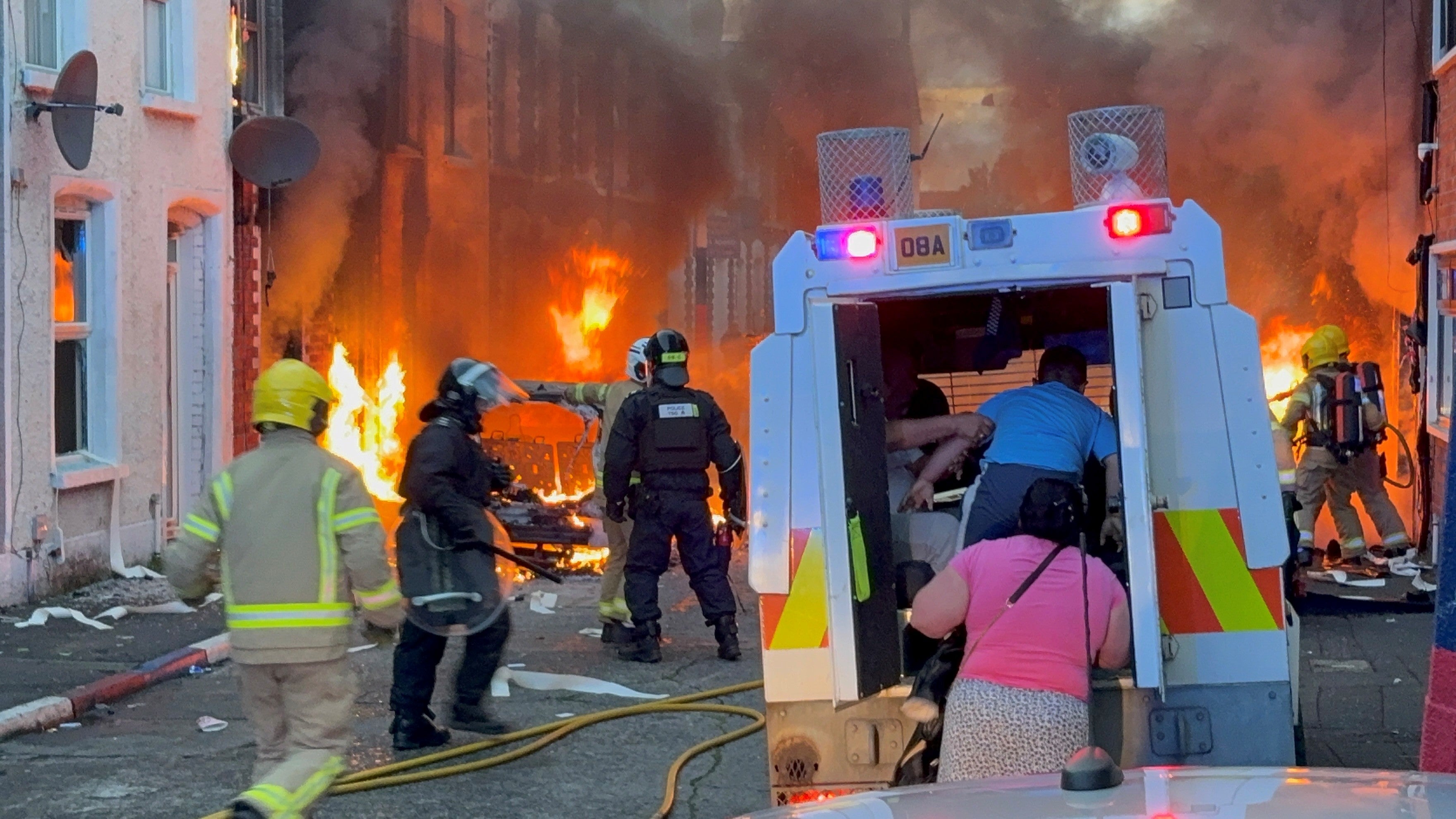 People seek safety in a police van as fires break out in a residential street