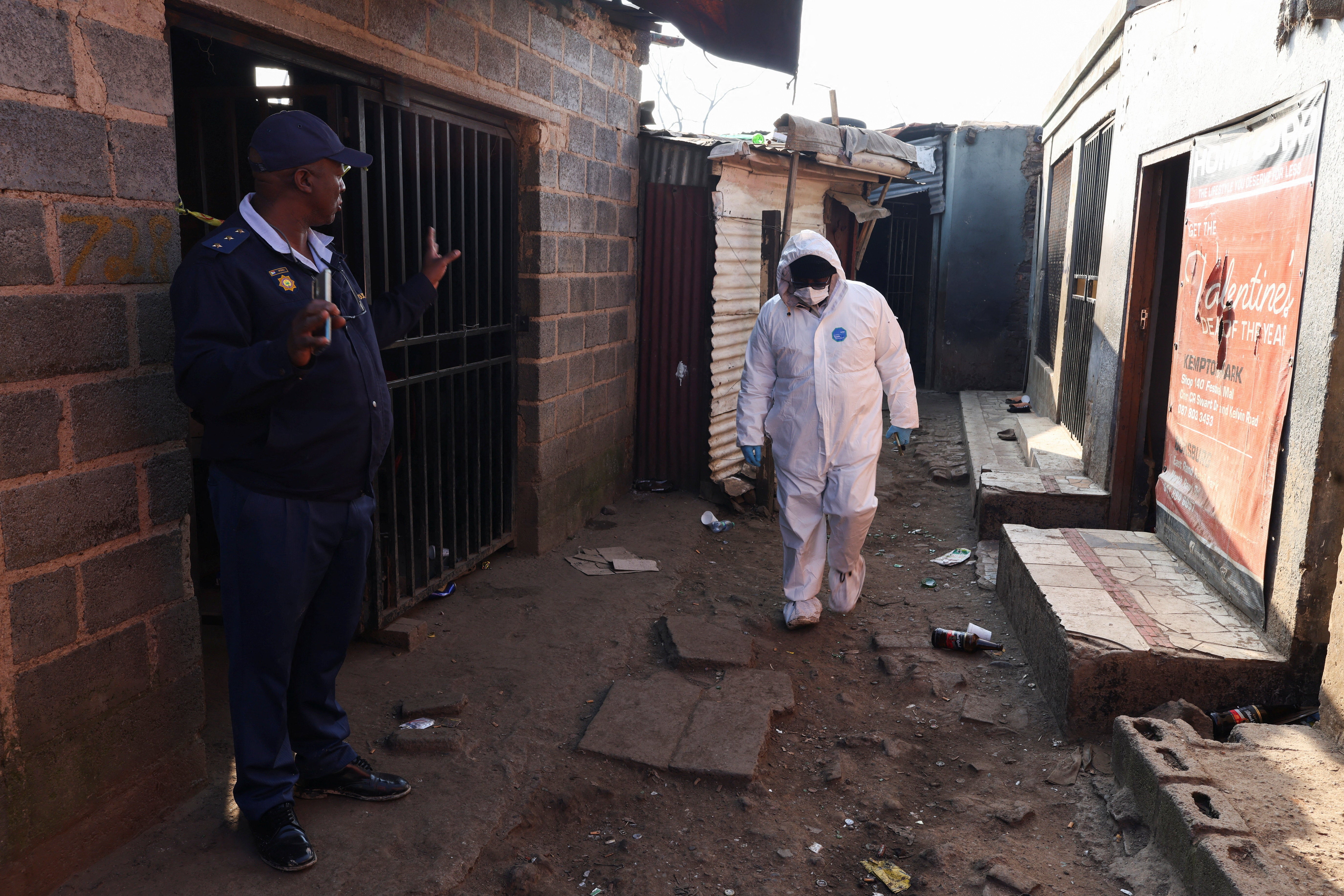 A Police oficer gestures next to a member of the forensics team after, according to the police, gunmen opened fire at an informal settlement in Cleveland, Johannesburg, South Africa,  June 10, 2026. REUTERS/Siphiwe Sibeko (Reuters)