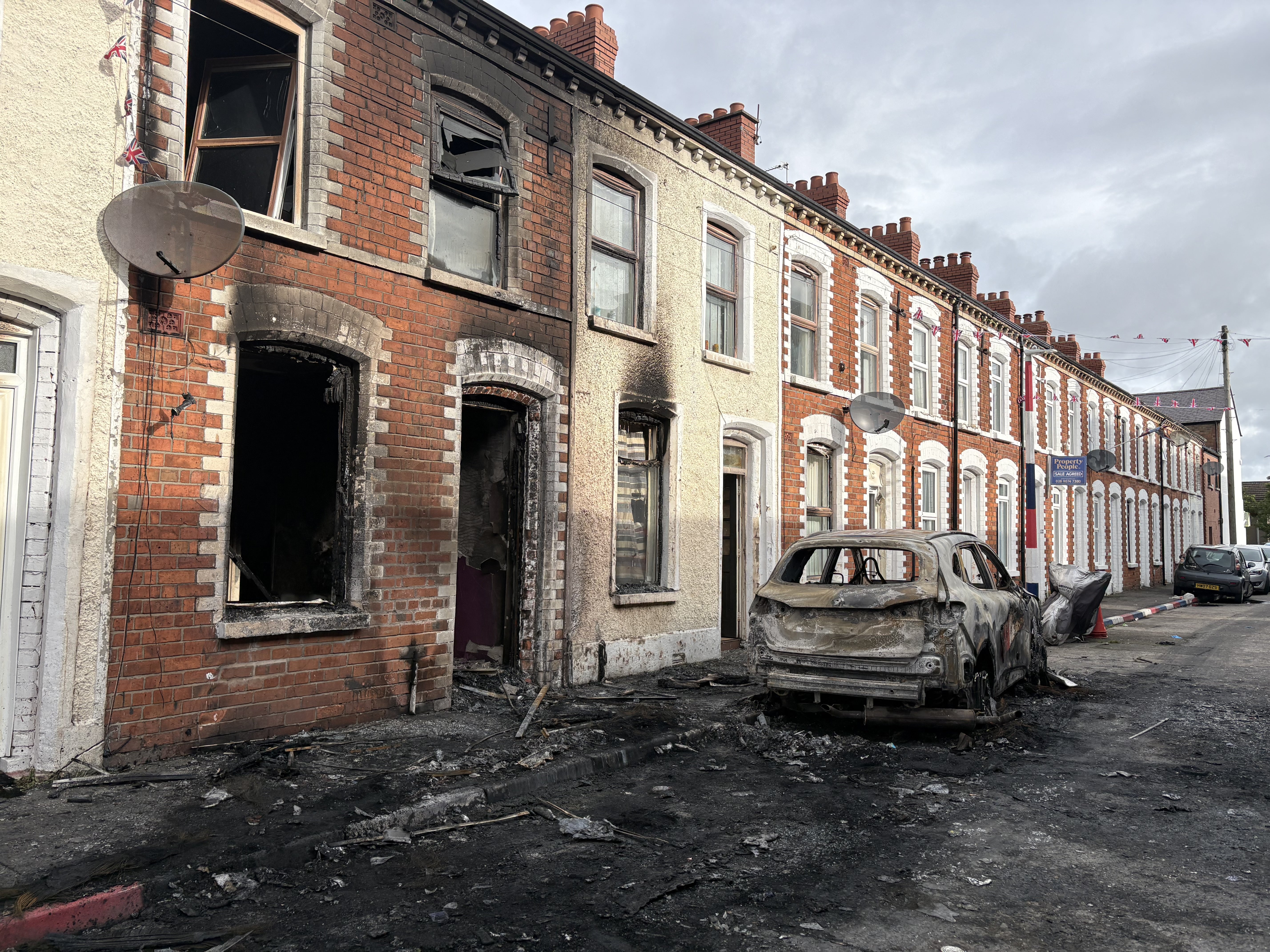 Burned-out cars and houses on Lendrick Street after Tuesday night’s disorder (PA) (PA Wire)