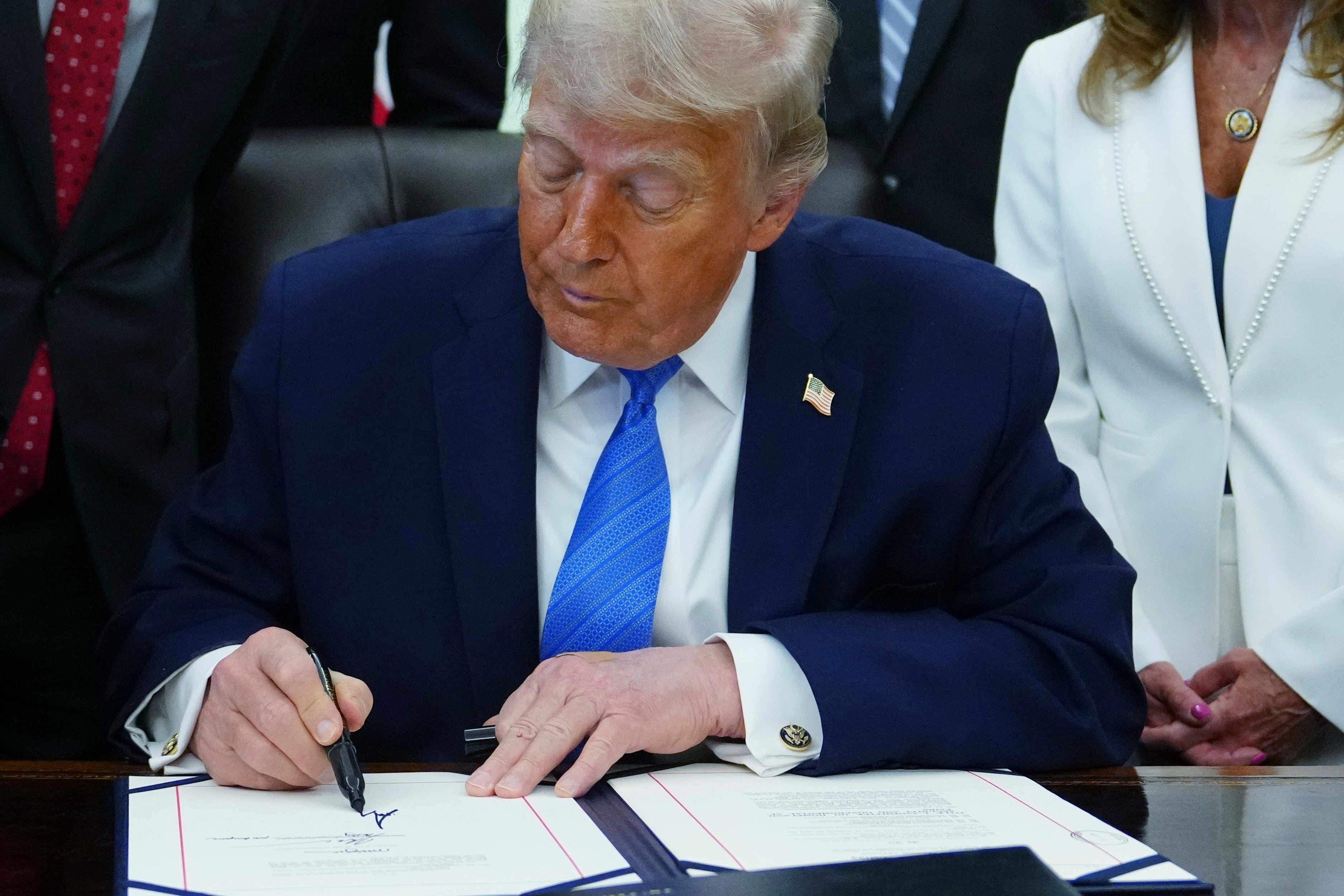 President Donald Trump signs a bill funding immigration enforcement after initially forgetting to sign and dismissing reporters