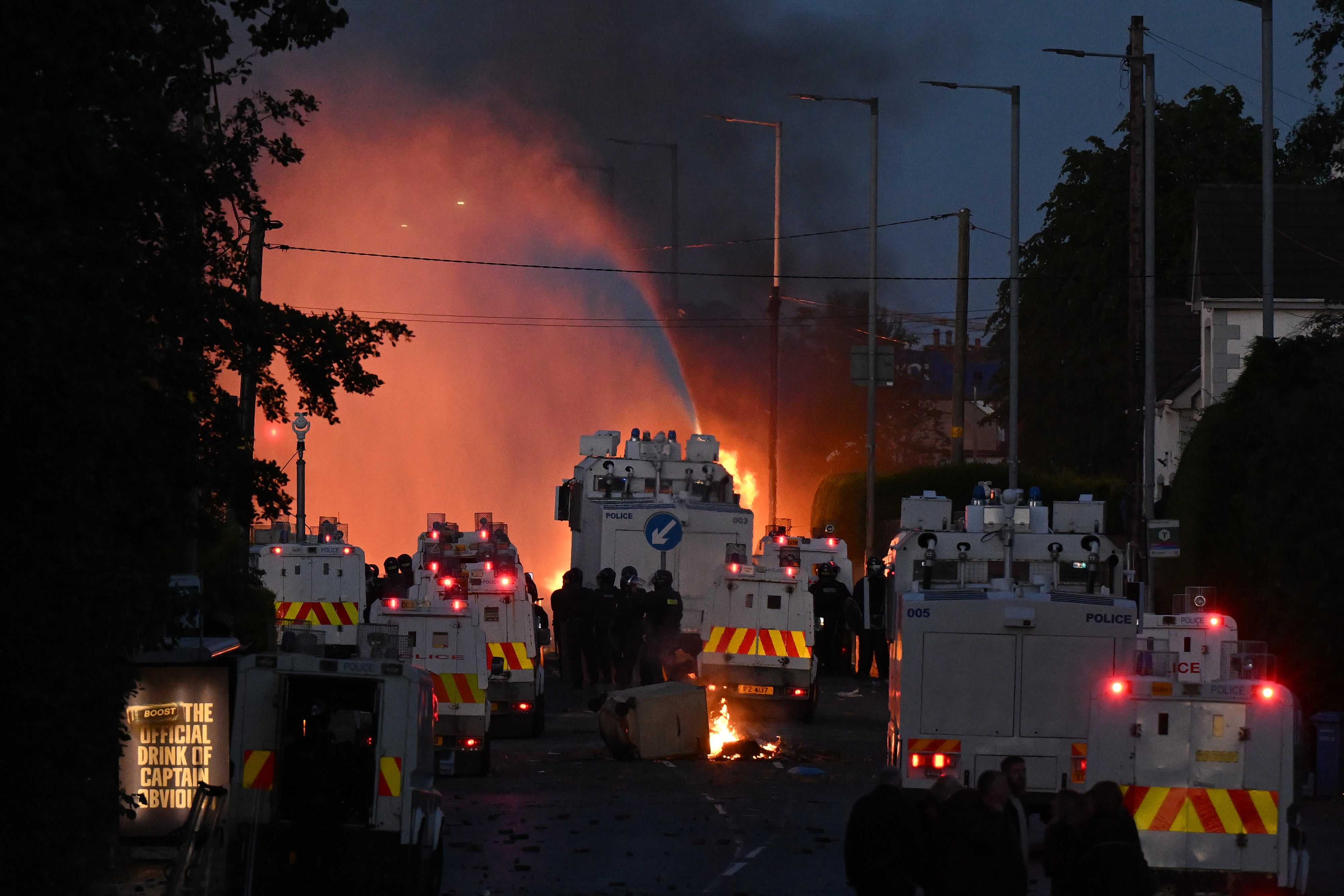 Police water canons spray water as fire burns during protests taking place near the Chimney Corner Hotel (Getty)