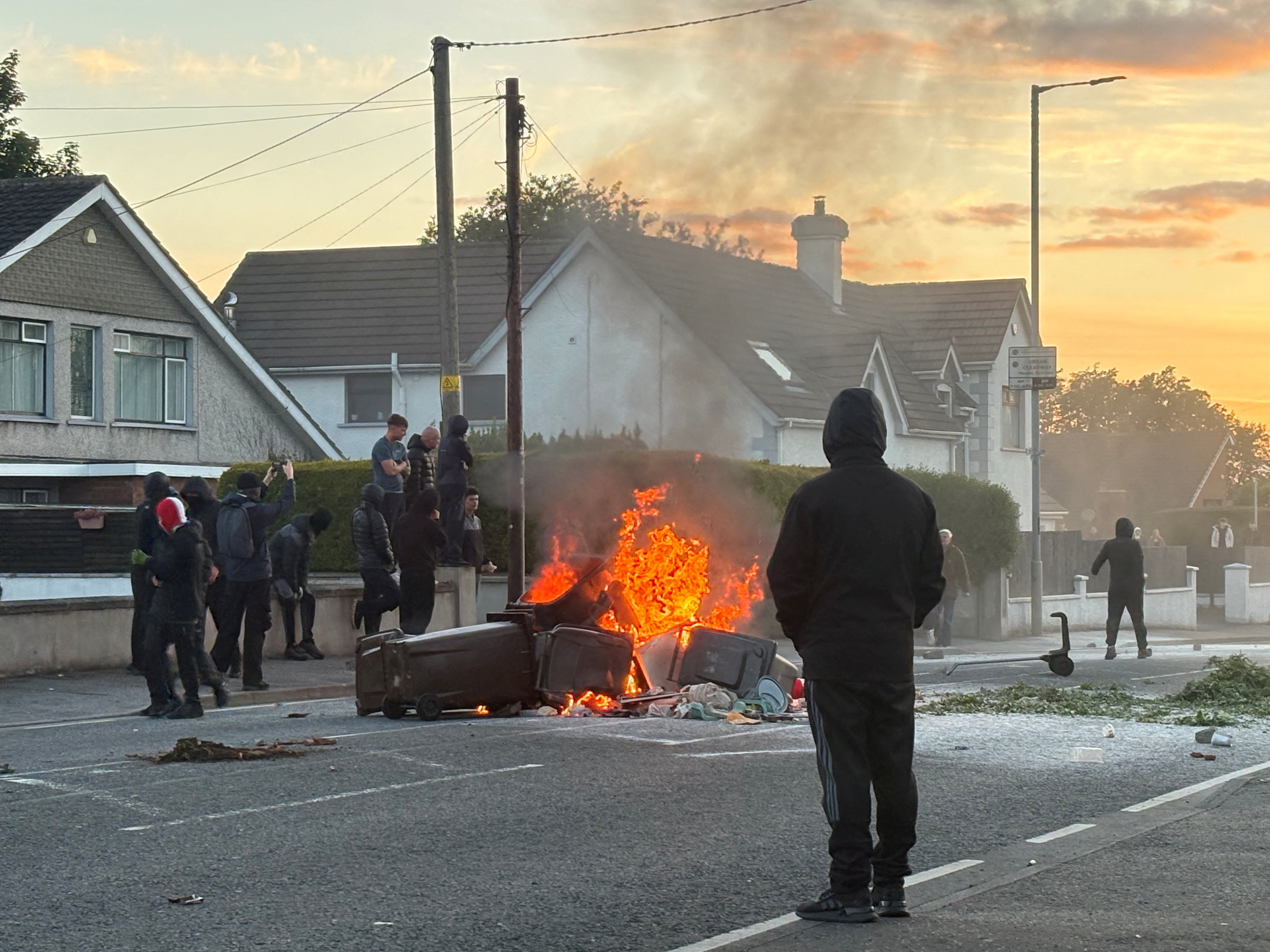 A fire burns in bins as anti-immigrant protesters clash with police at Antrim road, following a knife attack on June 8, which left a man seriously injured and prompted police to declare a critical incident, in Belfast.