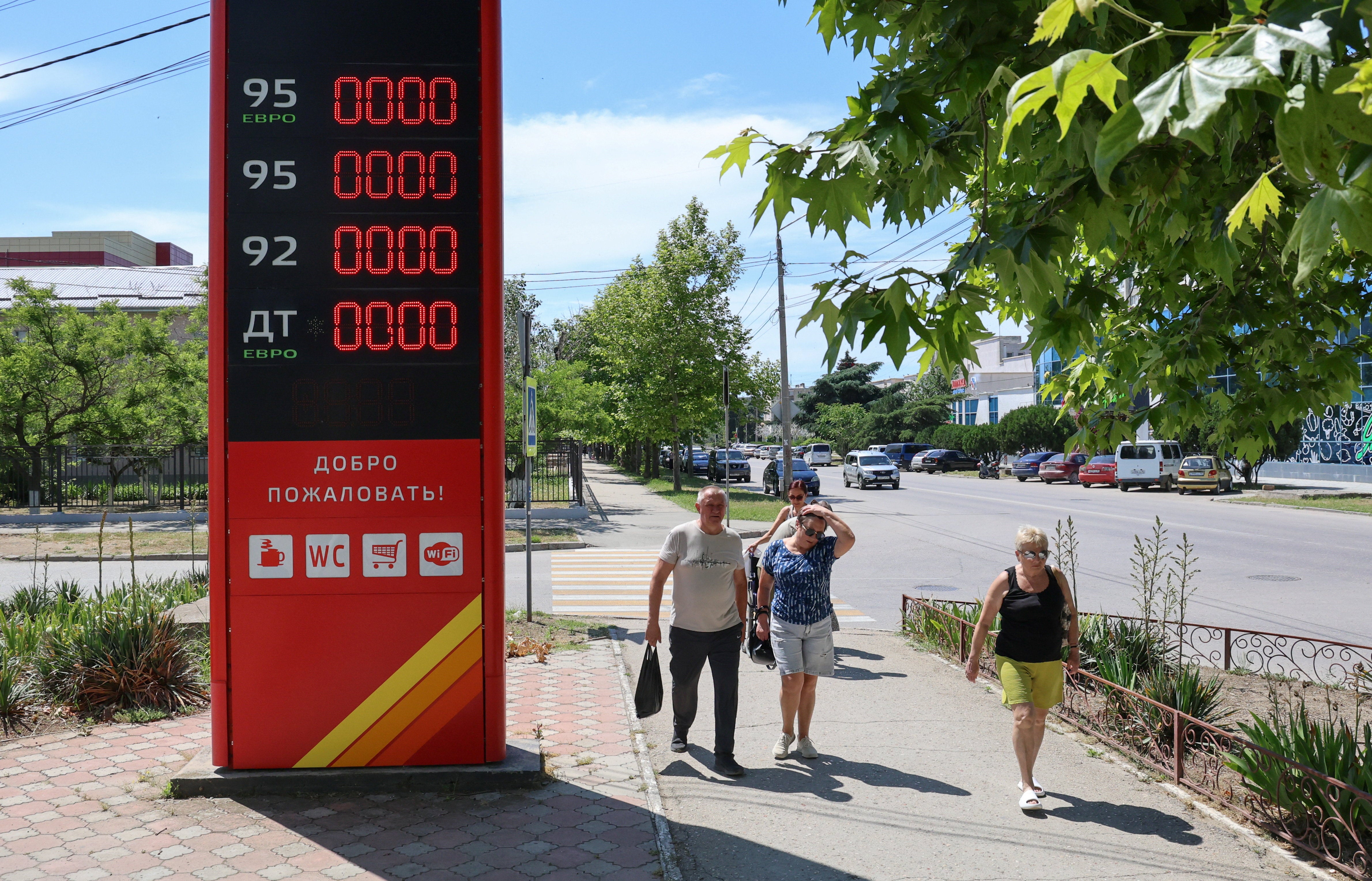 Pedestrians walk past a closed fuel station after local authorities restricted petrol sales and introduced rationing amid a supply shortage in the Black Sea resort city of Yevpatoriya, Crimea