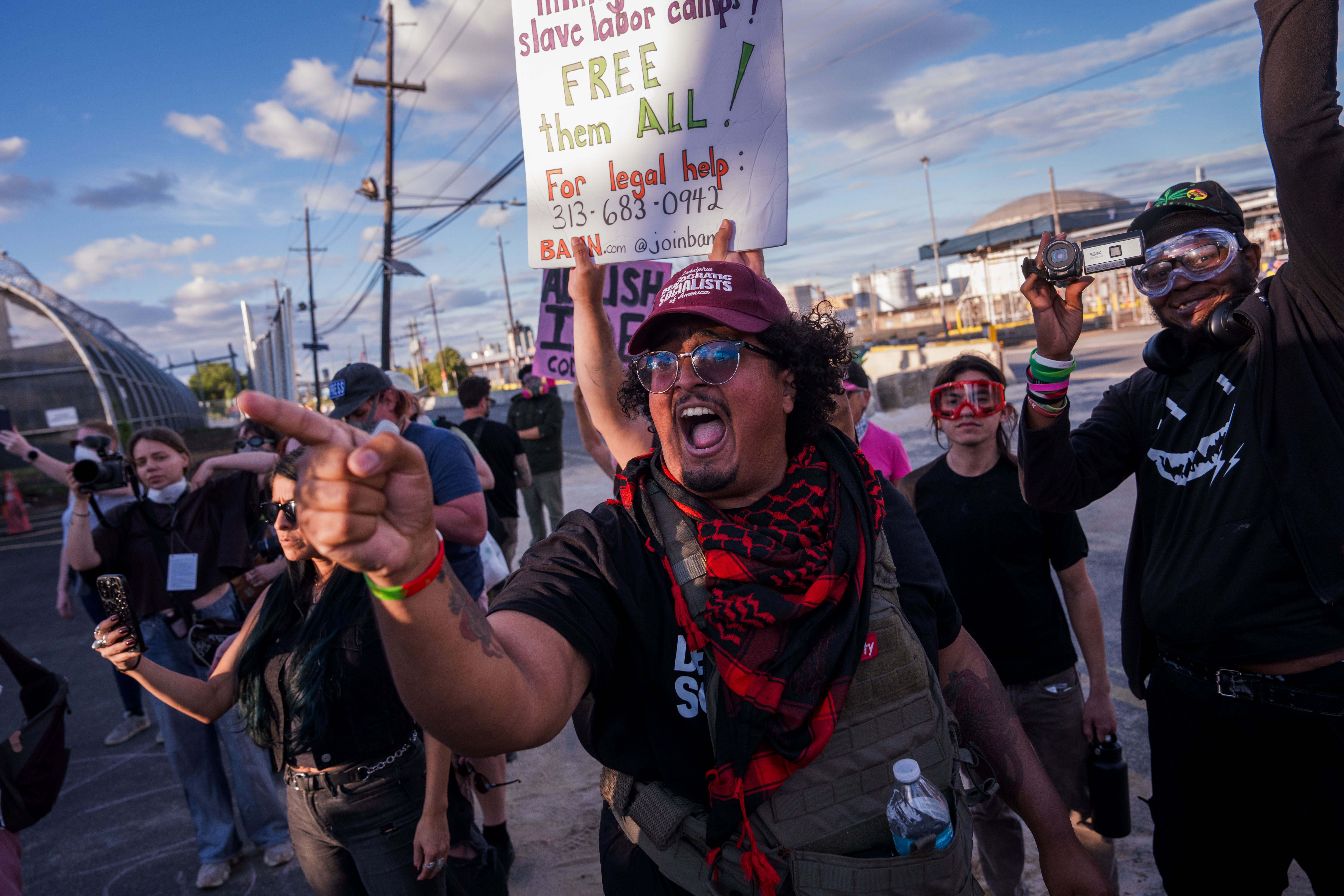 A demonstrator shouts at ICE agents and another holds a sign referencing ‘slave labor camps’ while protesting outside the Delaney Hall Immigration Detention Center in Newark, New Jersey, on June 7, 2026.