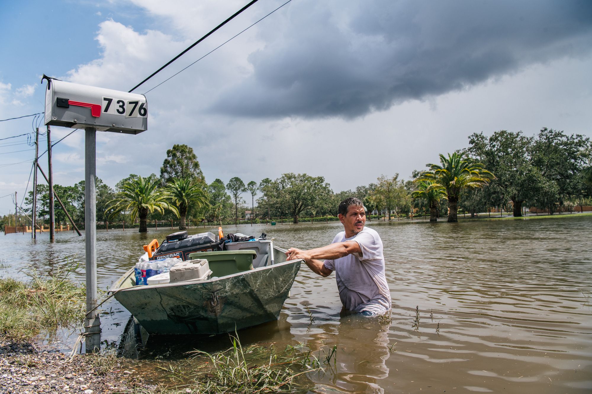A man pulls a boat through a flooded neighborhood following Hurricane Ida in Barataria, Louisiana, in August 2021. AI models rely on years of past weather data to help produce forecasts