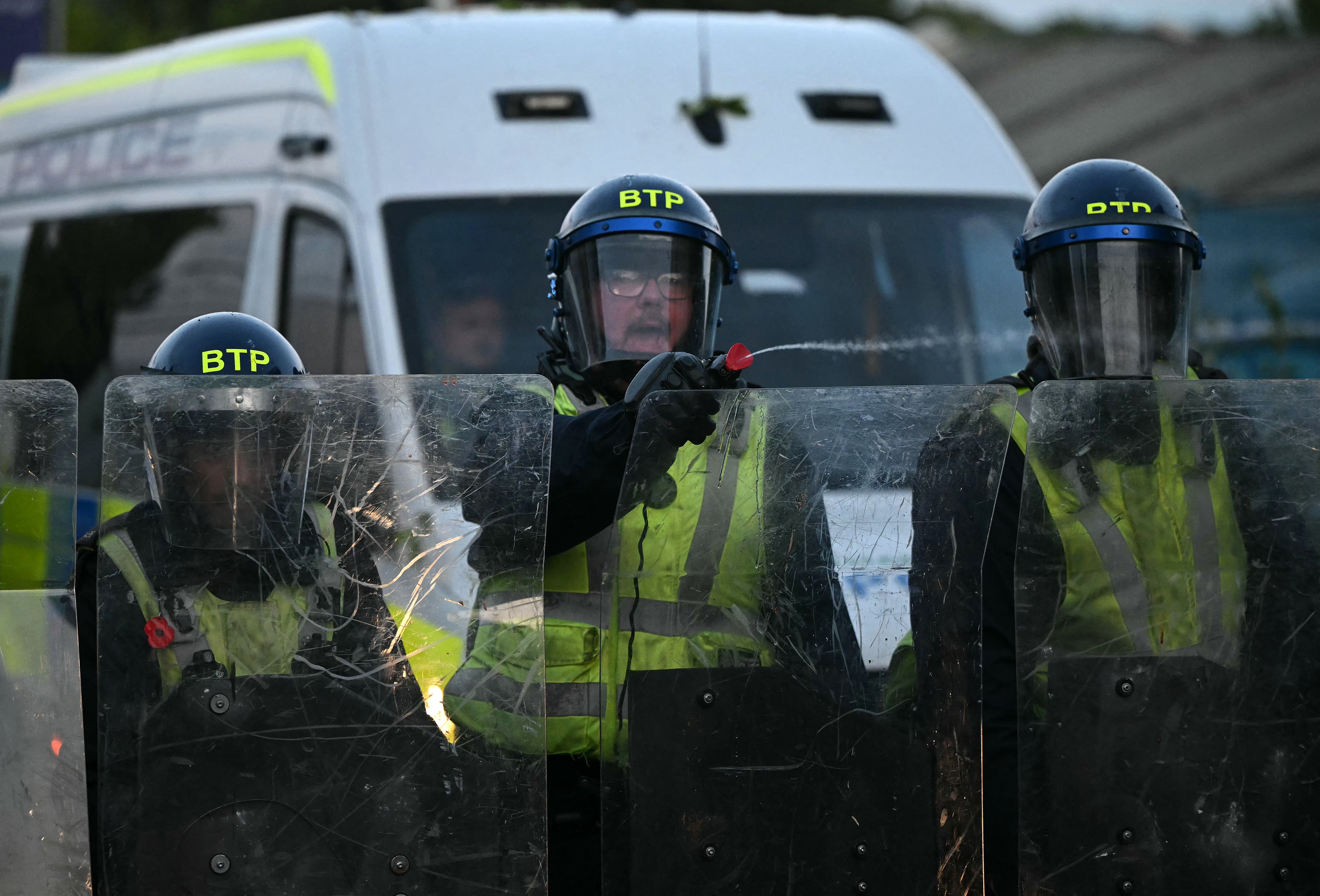 Police officers in riot gear spay demonstrators near Portswood Police Station in Southampton