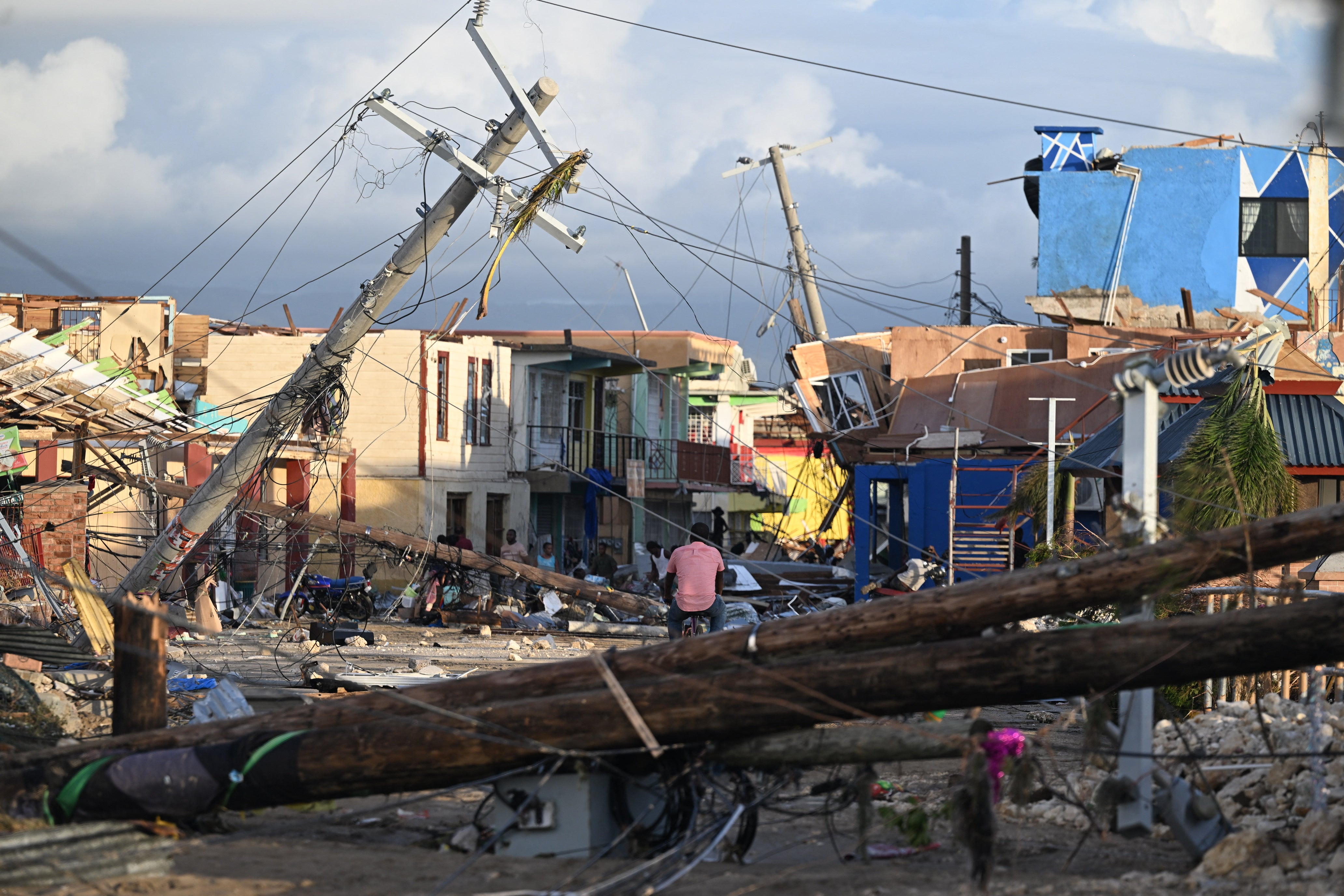 A man bikes through the destroyed neighborhood of North Street following the passage of Hurricane Melissa in Black River, Jamaica, in October 2025. Earlier forecasts helped better prepare people on the ground for the dangerous storm